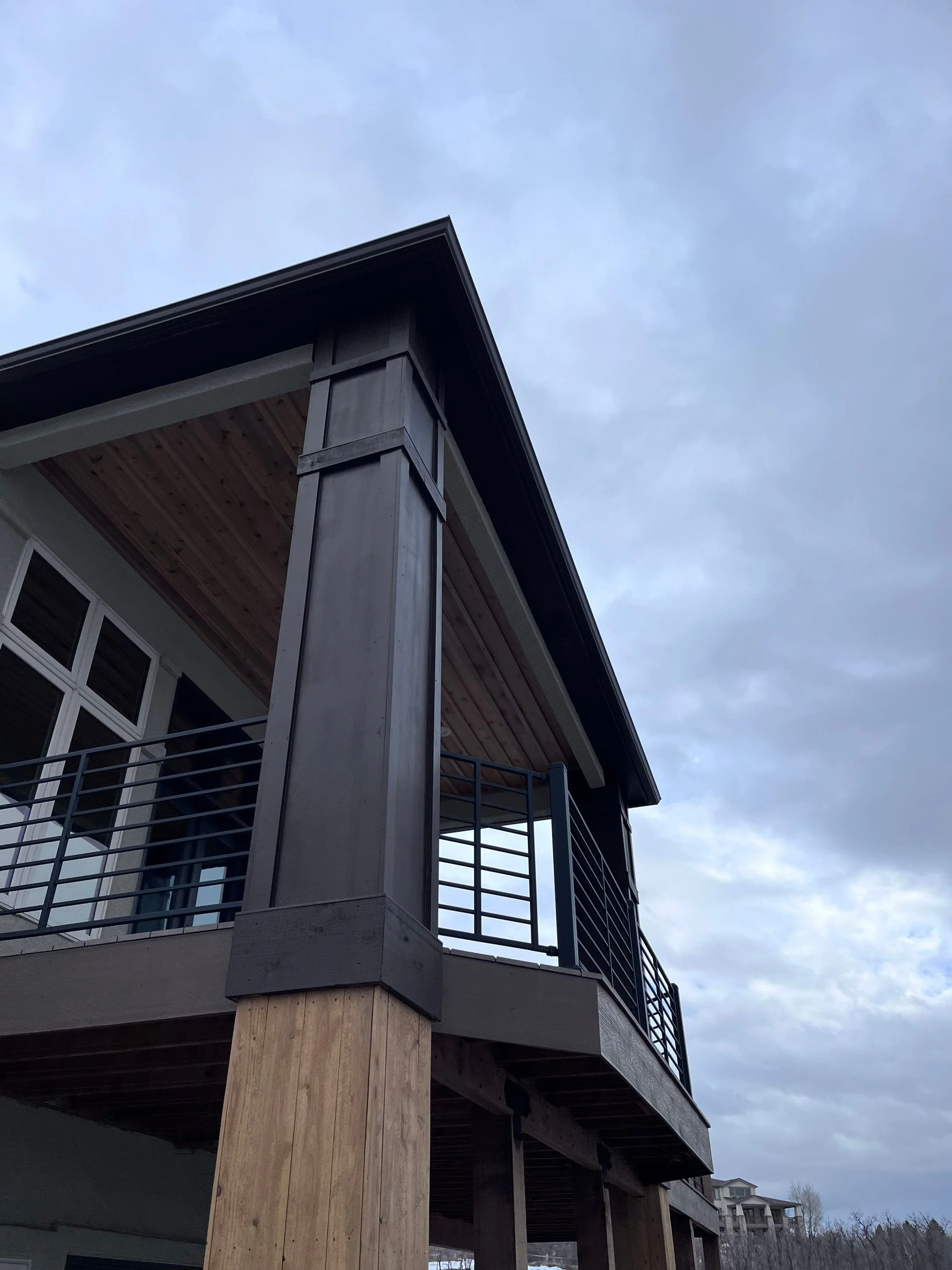 Dark bronze seamless gutter and downspout installed on the corner of a modern wood-sided home in the Denver Metro area.