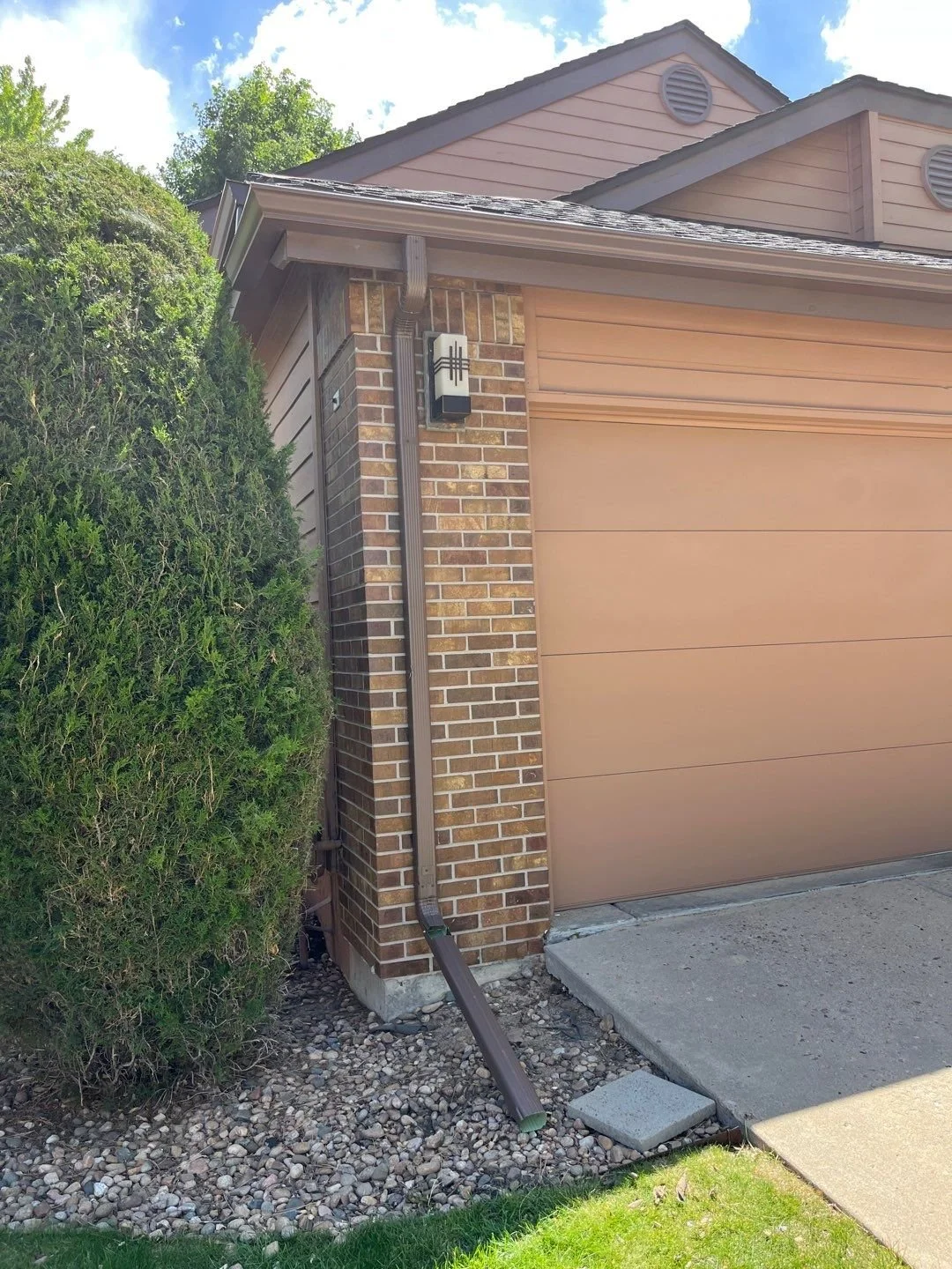 Gutter system installed beside a garage on a brick and siding home.