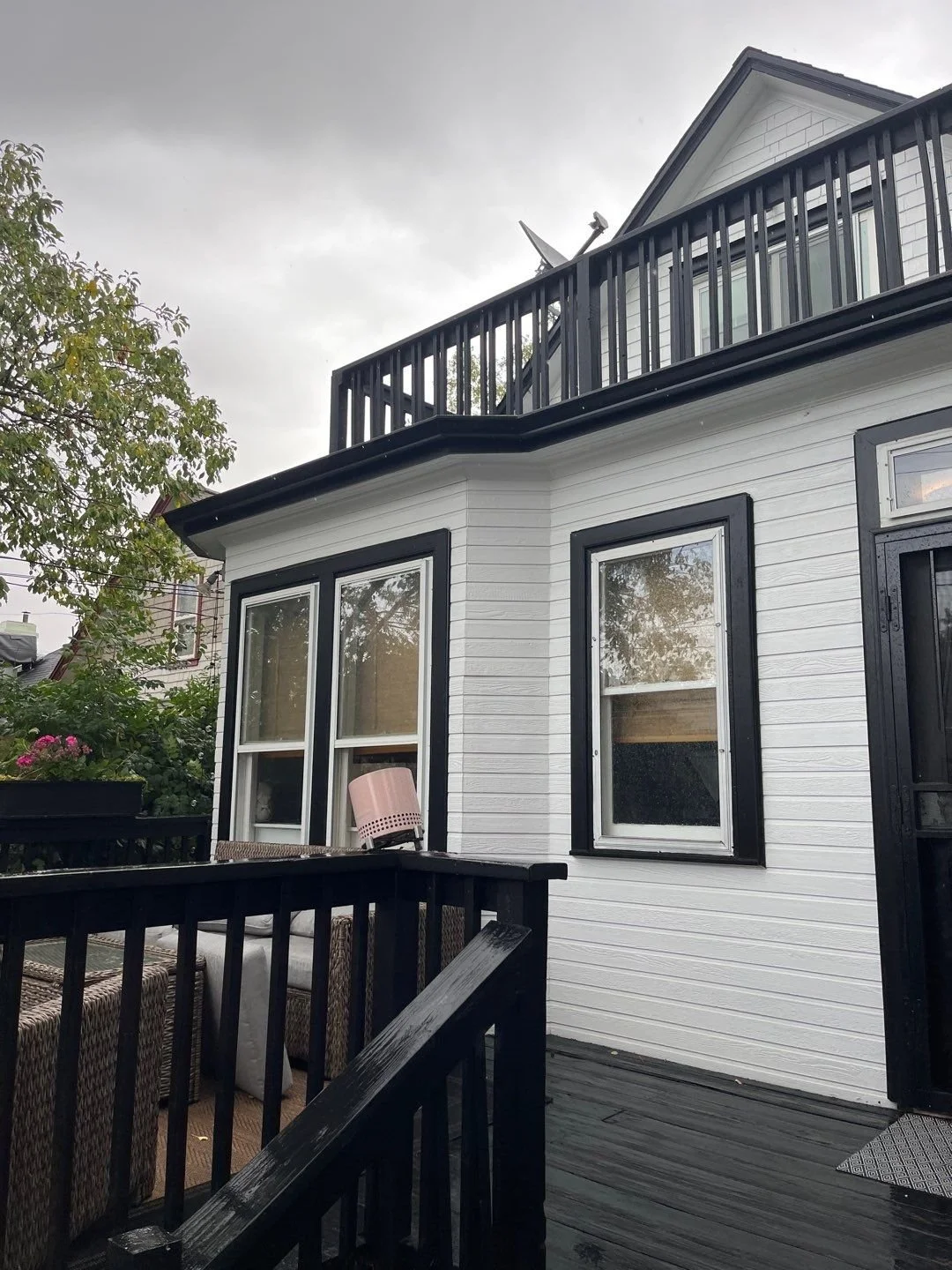Seamless gutters and downspouts installed on a light-sided home with a raised deck.