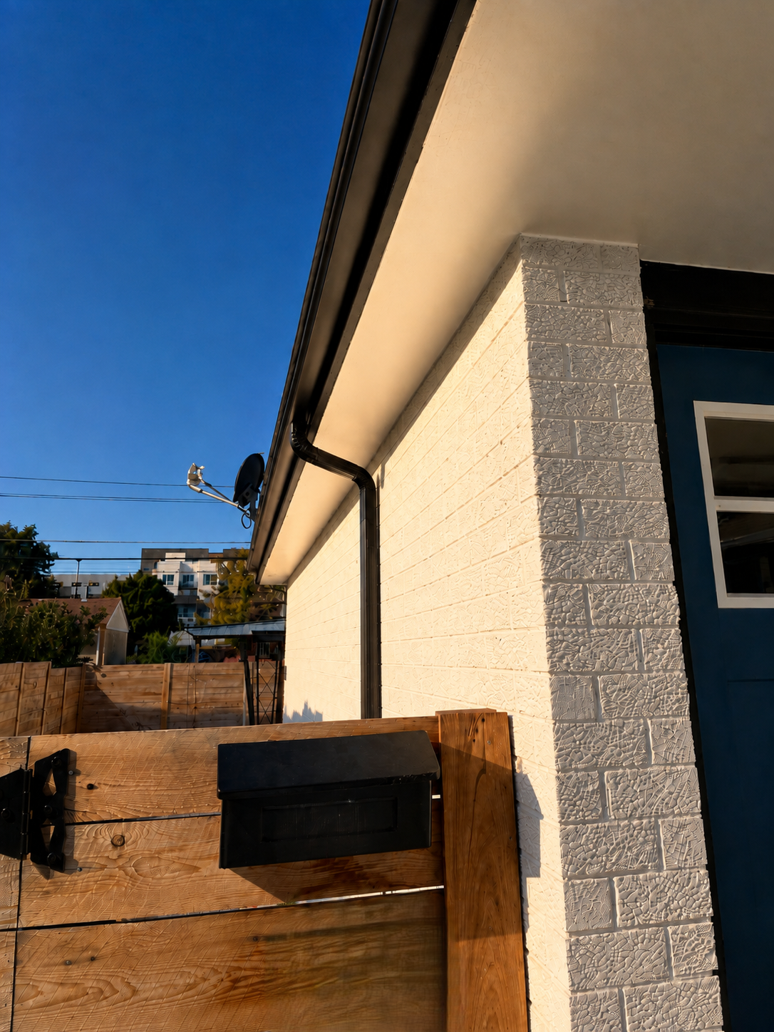 New black 2×3-inch downspout relocated to improve drainage on a home in Aurora, CO.
