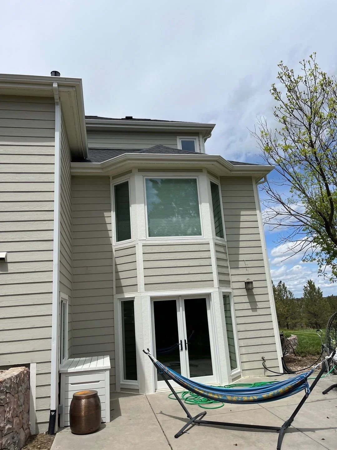 New white seamless gutters custom fitted around the upper and lower rear bay windows of a Bayou Hills home.
