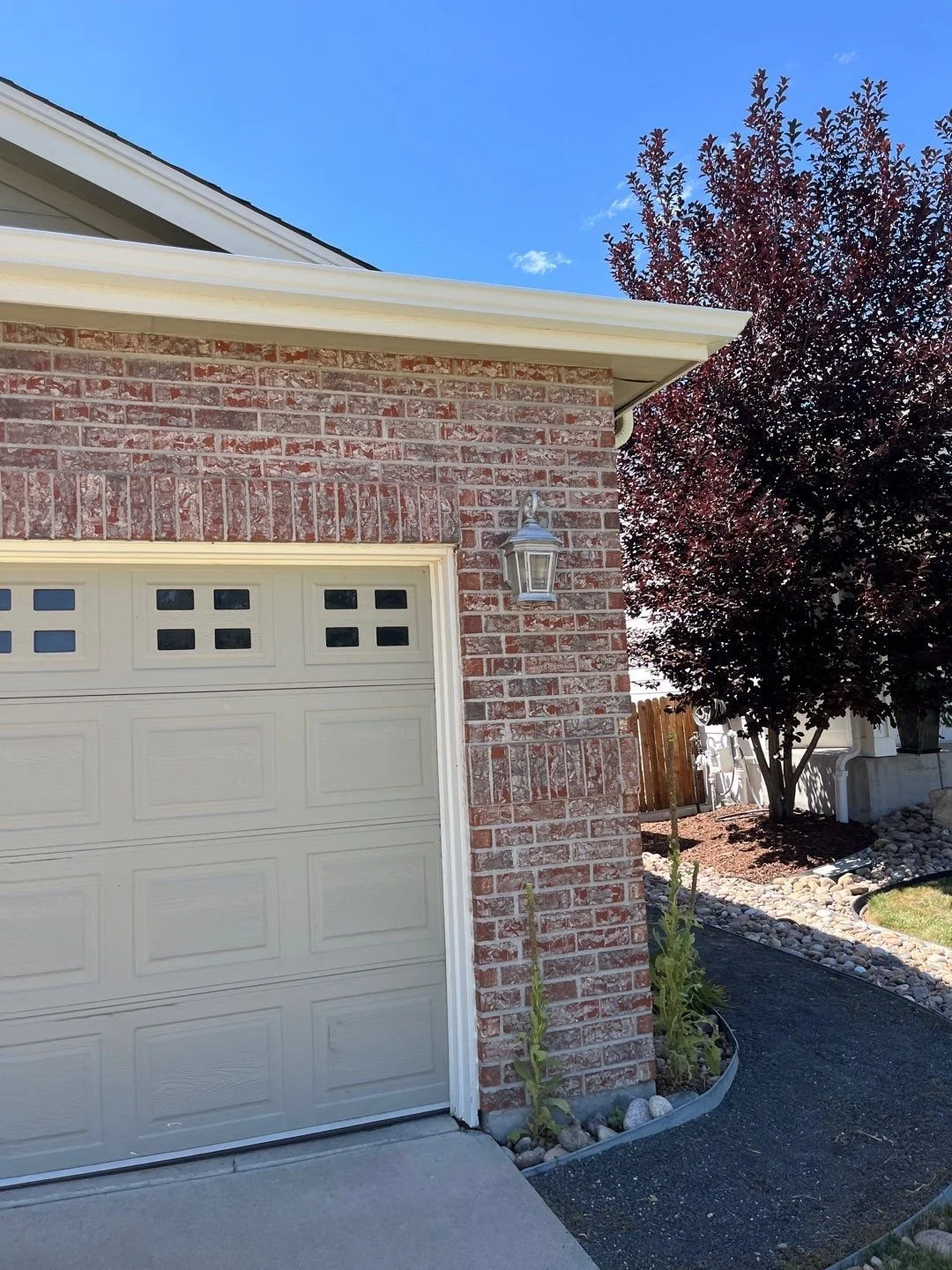 Gutter and downspout replacement completed along the brick garage and adjoining roof edge.
