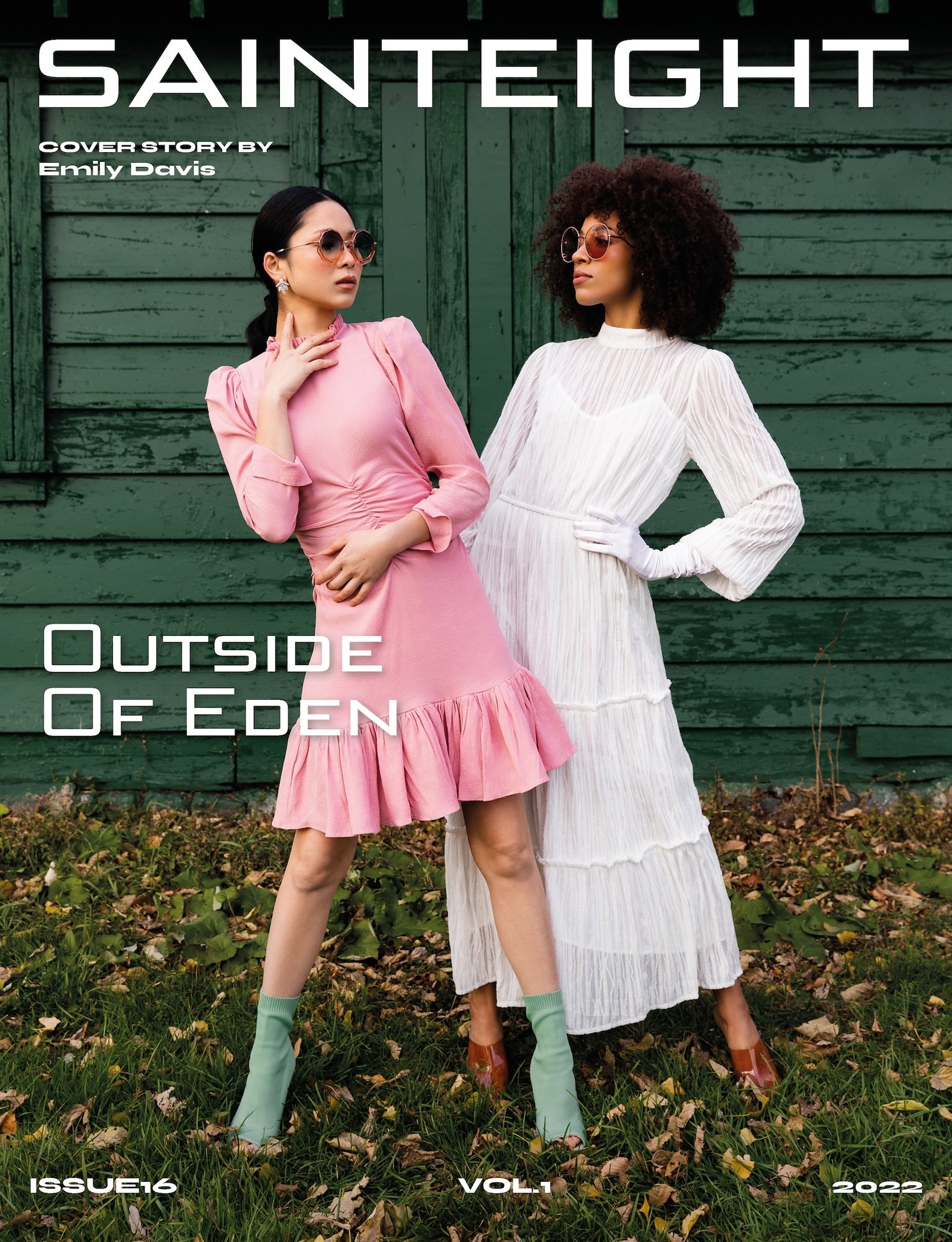 Magazine cover featuring two women in vintage-style outfits, one in a pink dress with ruffles and the other in a white tiered dress, standing outdoors with a green wooden building in the background.