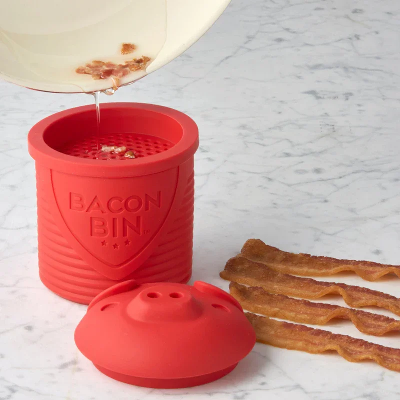 small red, silicone container for saving bacon grease. the lid looks like a pig's face.