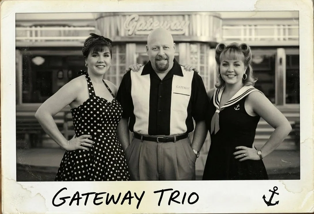 Black and white photo of two women and one man in vintage clothing standing in front of a building with a sign that reads 'Gateway'. The woman on the left is in a polka dot dress, and the woman on the right in a sailor dress, both smiling with hands 