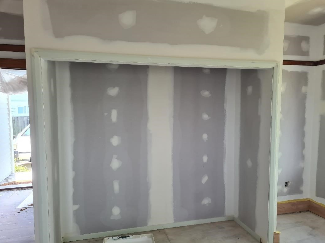 Interior wall with drywall in the process of being finished, with drywall joints taped and mudded, but not yet painted.