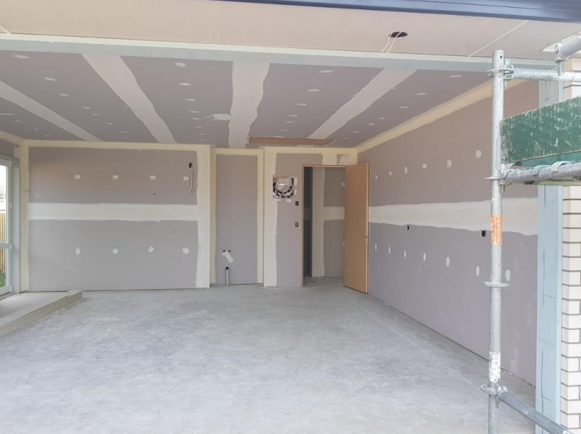 Interior of a room under construction or renovation with drywall and some scaffolding on the side.