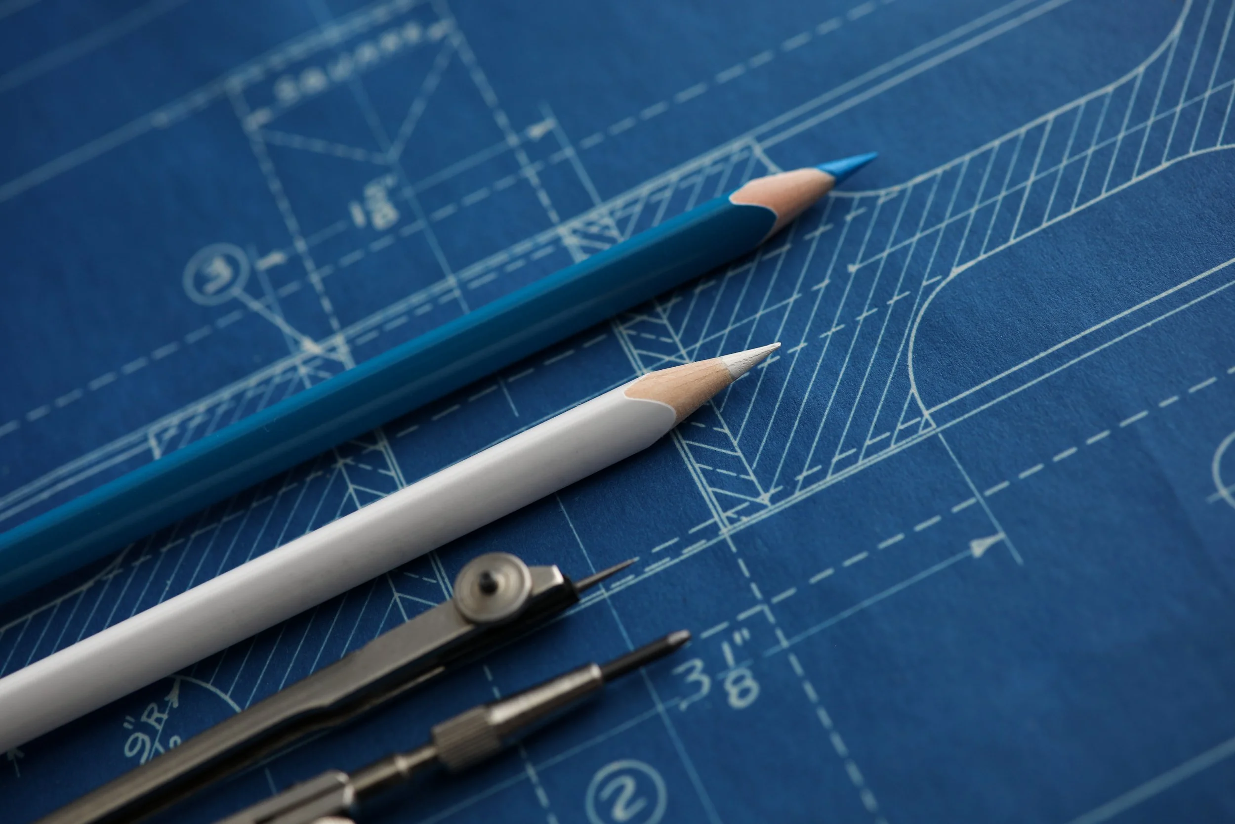 Drafting pencils and tools lie atop a blueprint