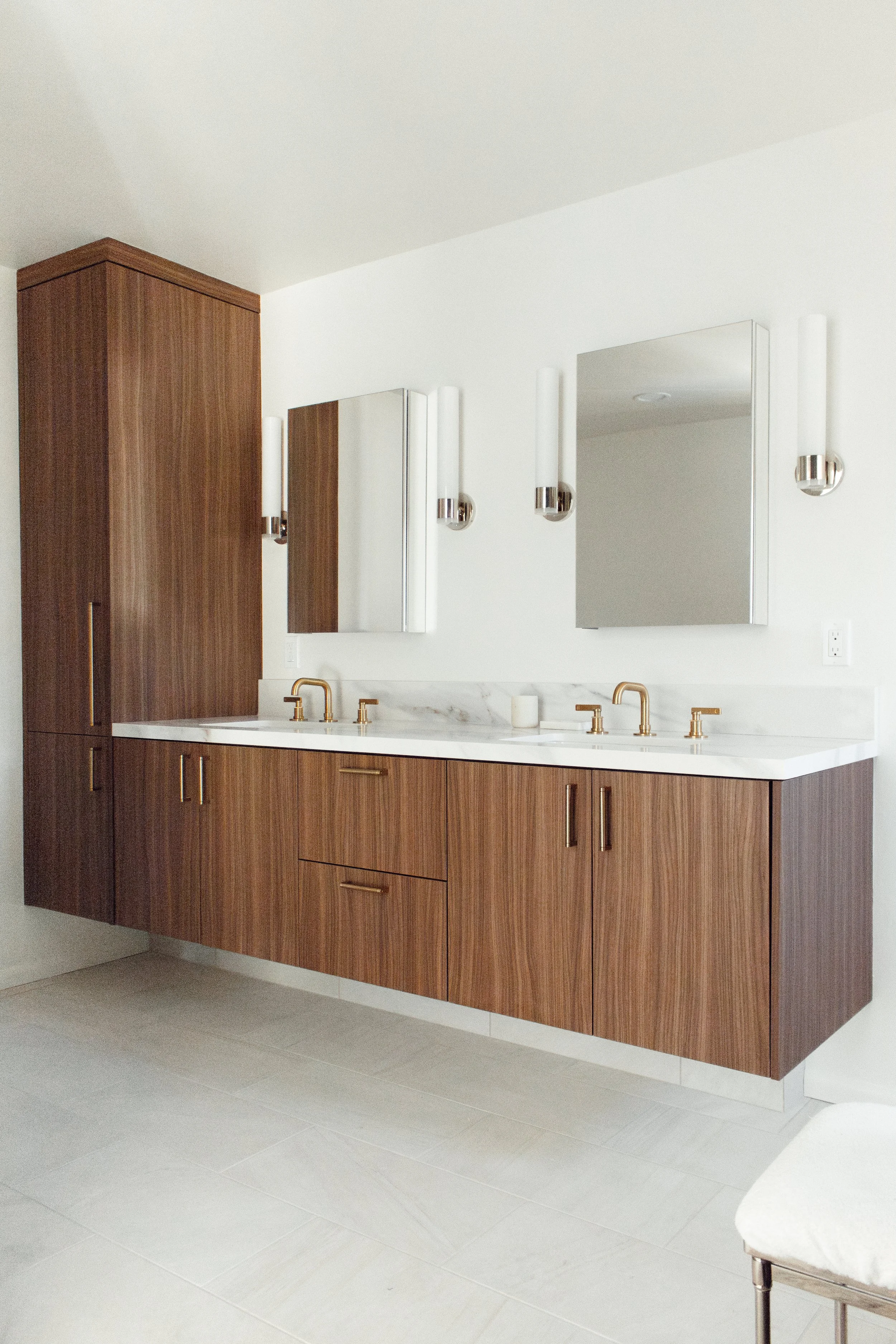 Mid-century modern style, floating bathroom cabinet with marble countertops, gold fixtures, and a tower cabinet on the left. Cabinets made out of Cleaf LS54 Catillo material, capturing the look of rich, modern walnut with enhanced durability
