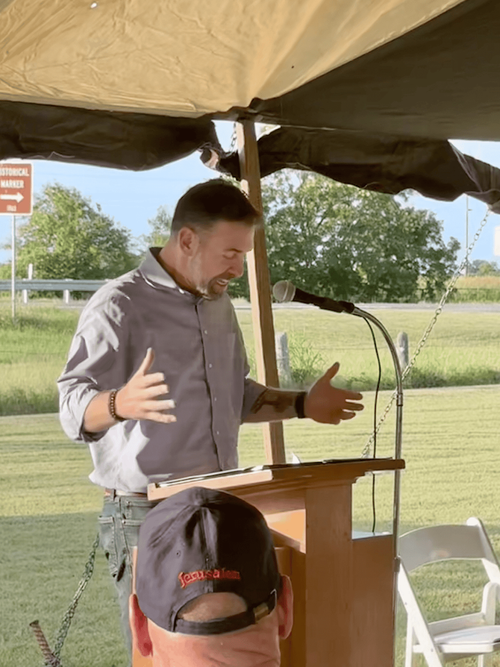 Grant Reed preaching under a revival tent