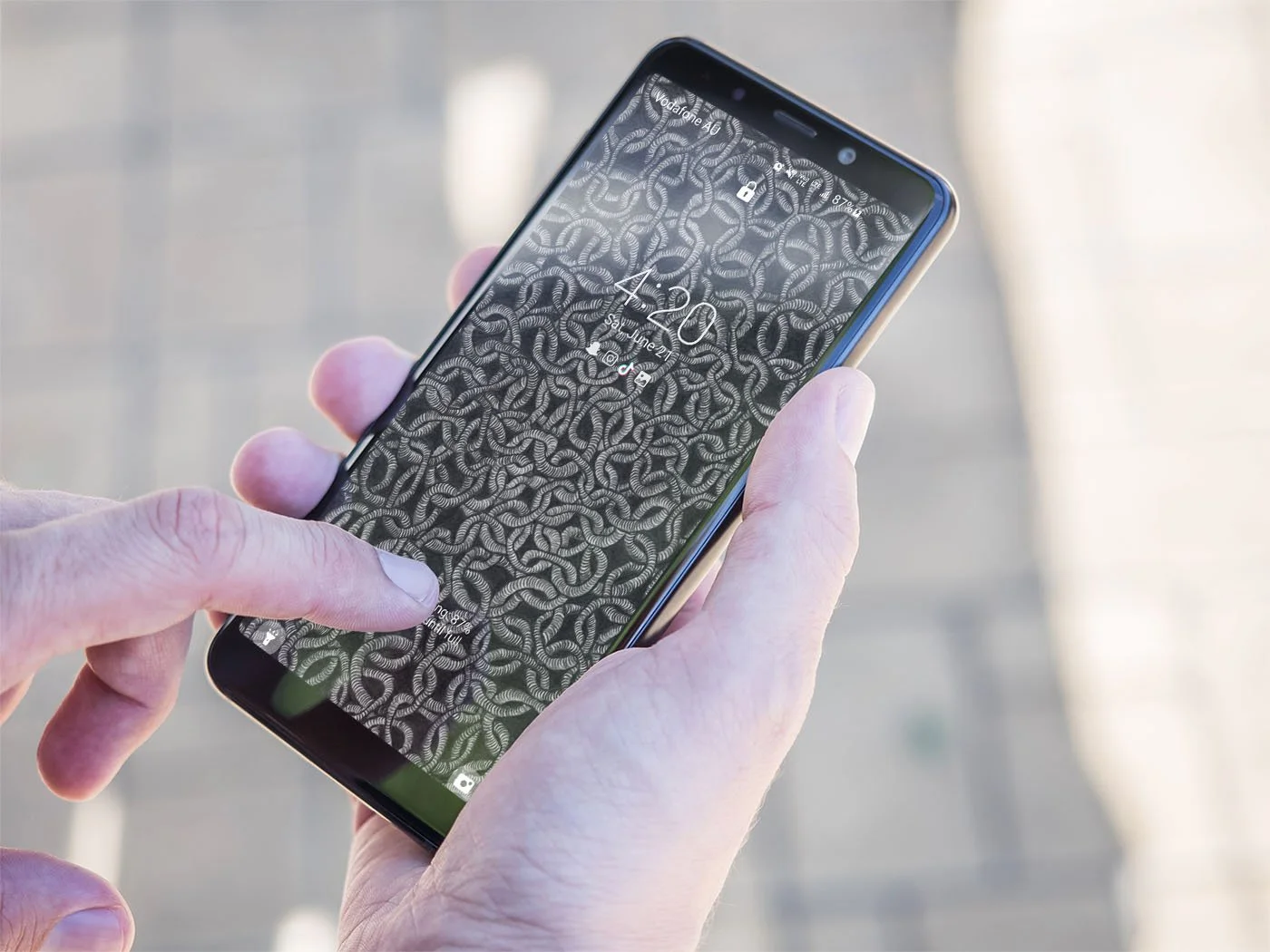 Person-holding-android-phone-with-black-and-white-line-art-wallpaper-over-sunny-blurry-background.jpg