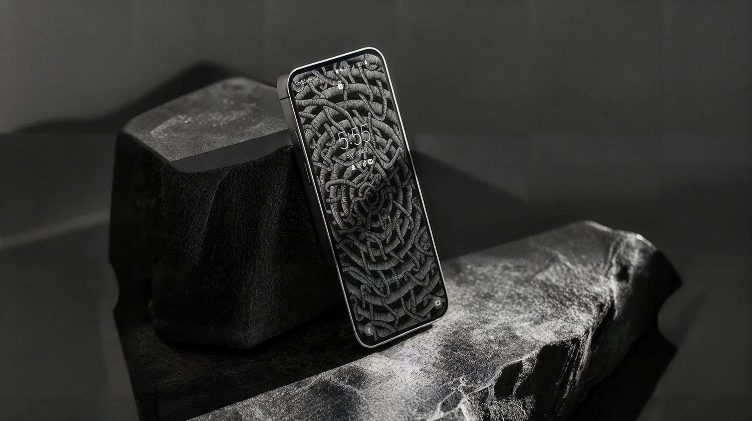 Iphone-with black-and-white line-art-wallpaper-with-lockscreen-standing-tilted-against-two-rocks.jpg