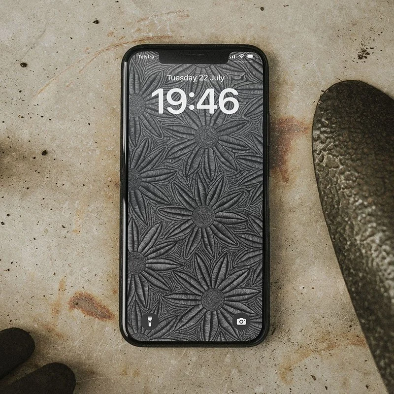 Iphone-with-black-and-white-line-art-wallpaper-and-lockscreen-standing-laying-on-stone-surface-with-shovel-and-gloves