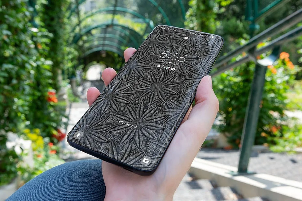 Women-sitting-on-steps-holding-samsung-phone-with-black-and-white-line-art-wallpaper-with-trees-and-plants-in-background