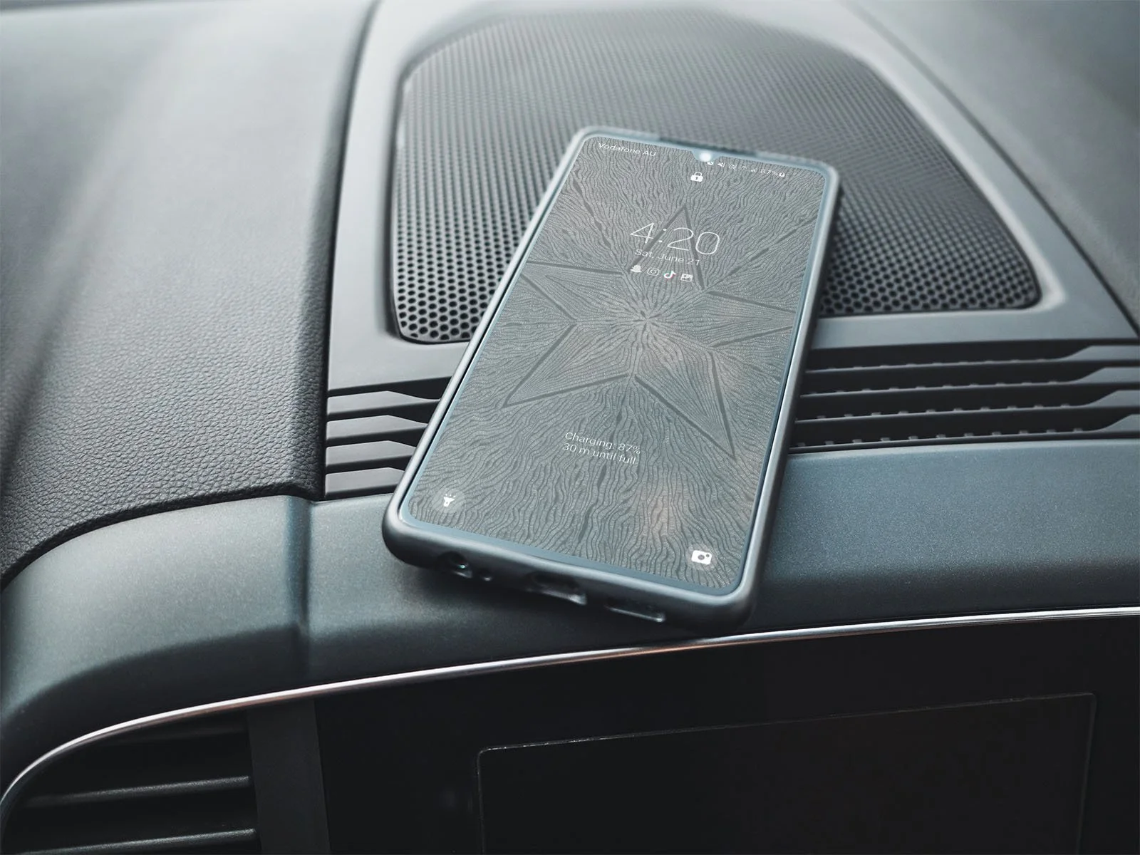 Samsung-phone-with-black-and-white-line-art-wallpaper-lockscreen-laying-on black-car-dashboard.jpg