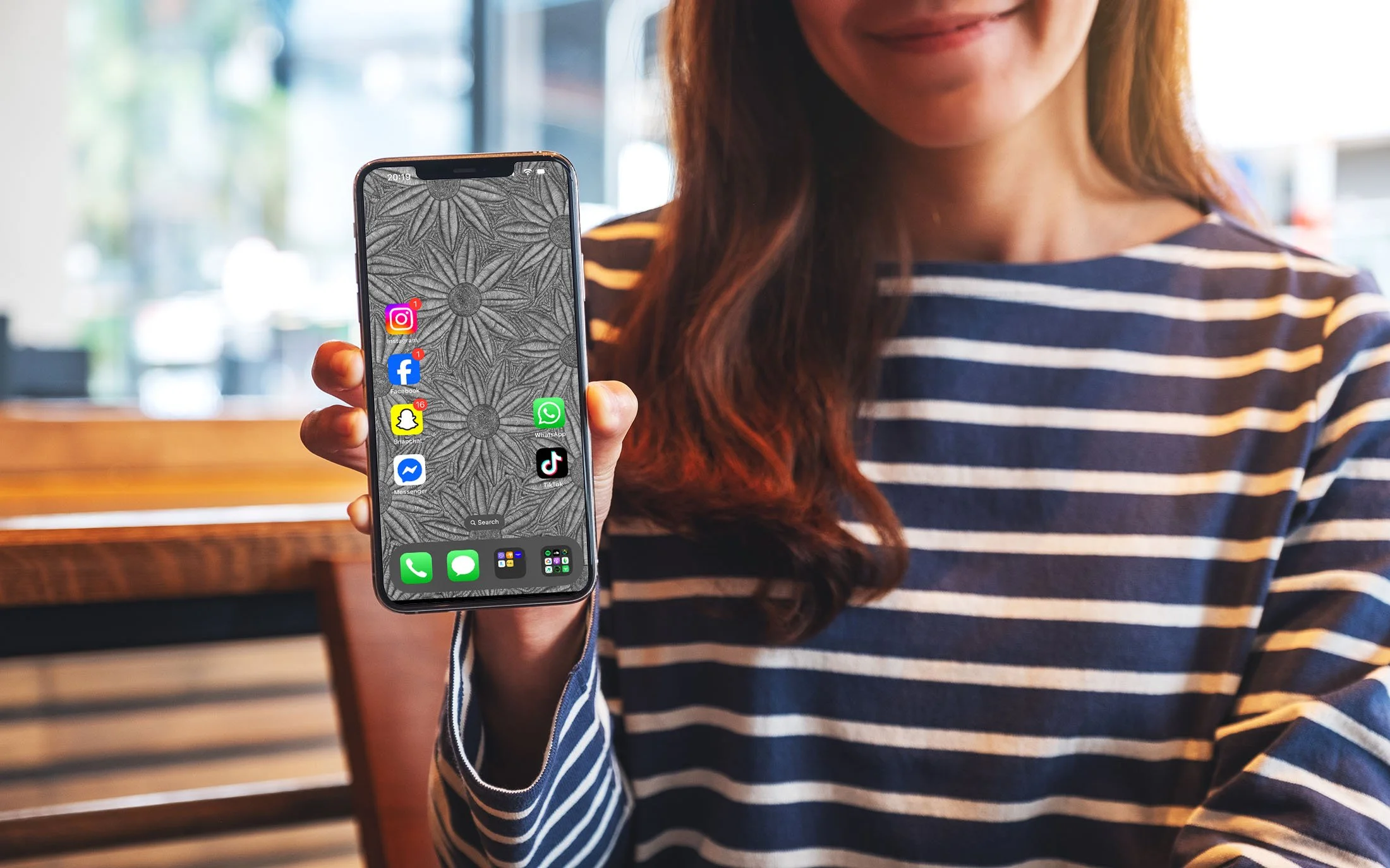 Girl-holding-Iphone-with-black-and-white-line-art-wallpaper-with-app-icons-over-cafe-background.jpg