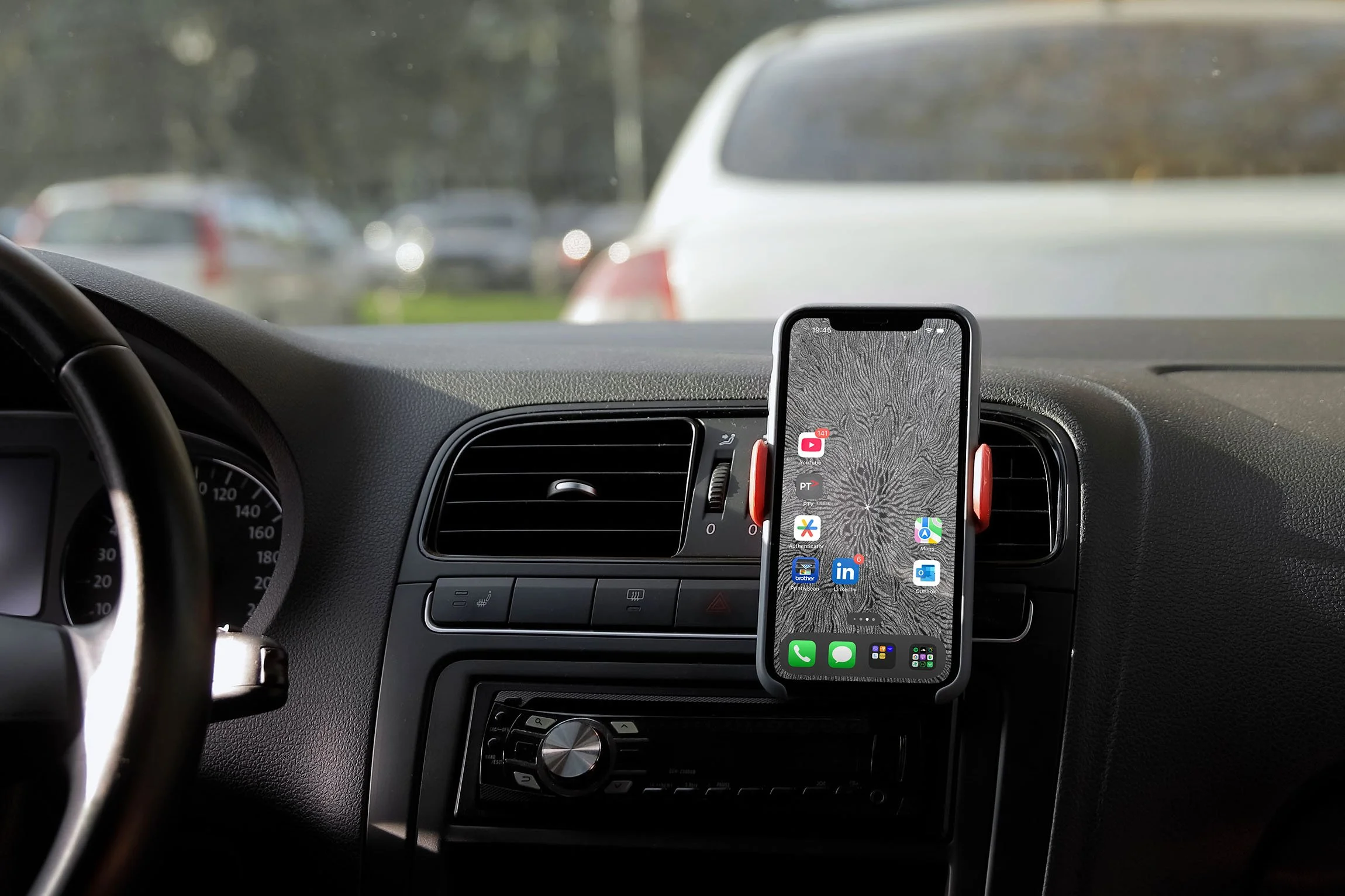 Iphone-with black-and-white line-art-wallpaper-with-homescreen-and-app-icons-mountied-to-a-dock-in-the-car