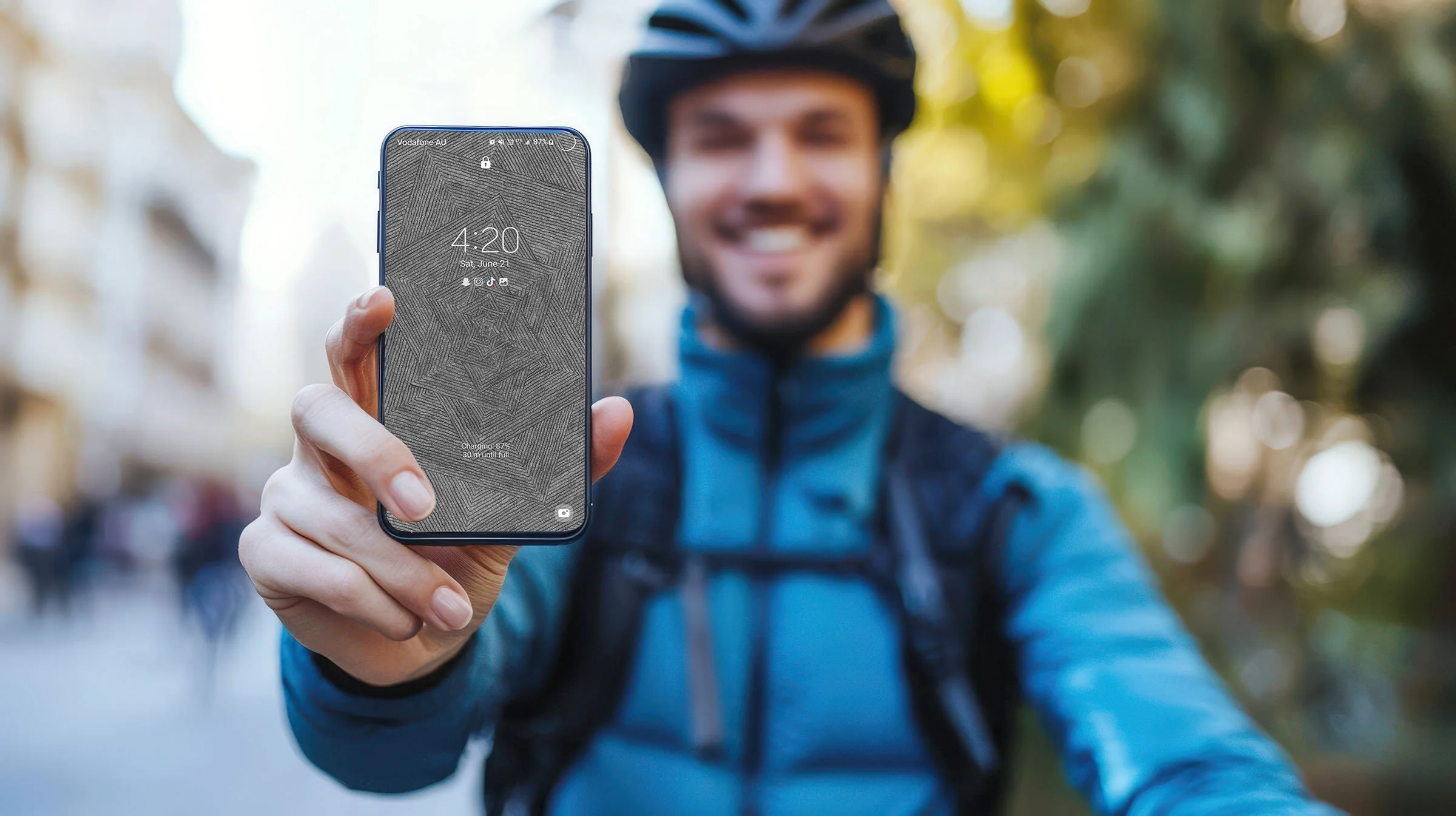 Man-onbicycle-wearing-blue-holdingandroid-phone-with-black-and-white-line-art-wallpaper-with-lockscreen-over-blurred-city-streets-background.jpg