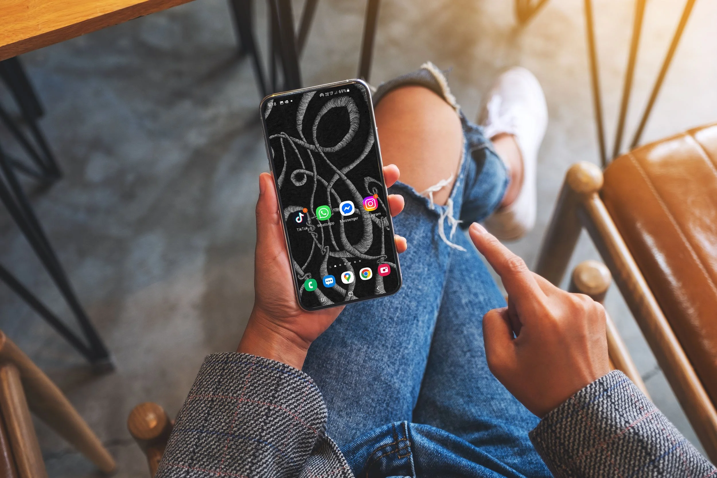 Women-sitting-wearing-ripped-blue-jeans-holding-android-phone-with-unsonscious-flow-line-art-and-app-icons.jpg