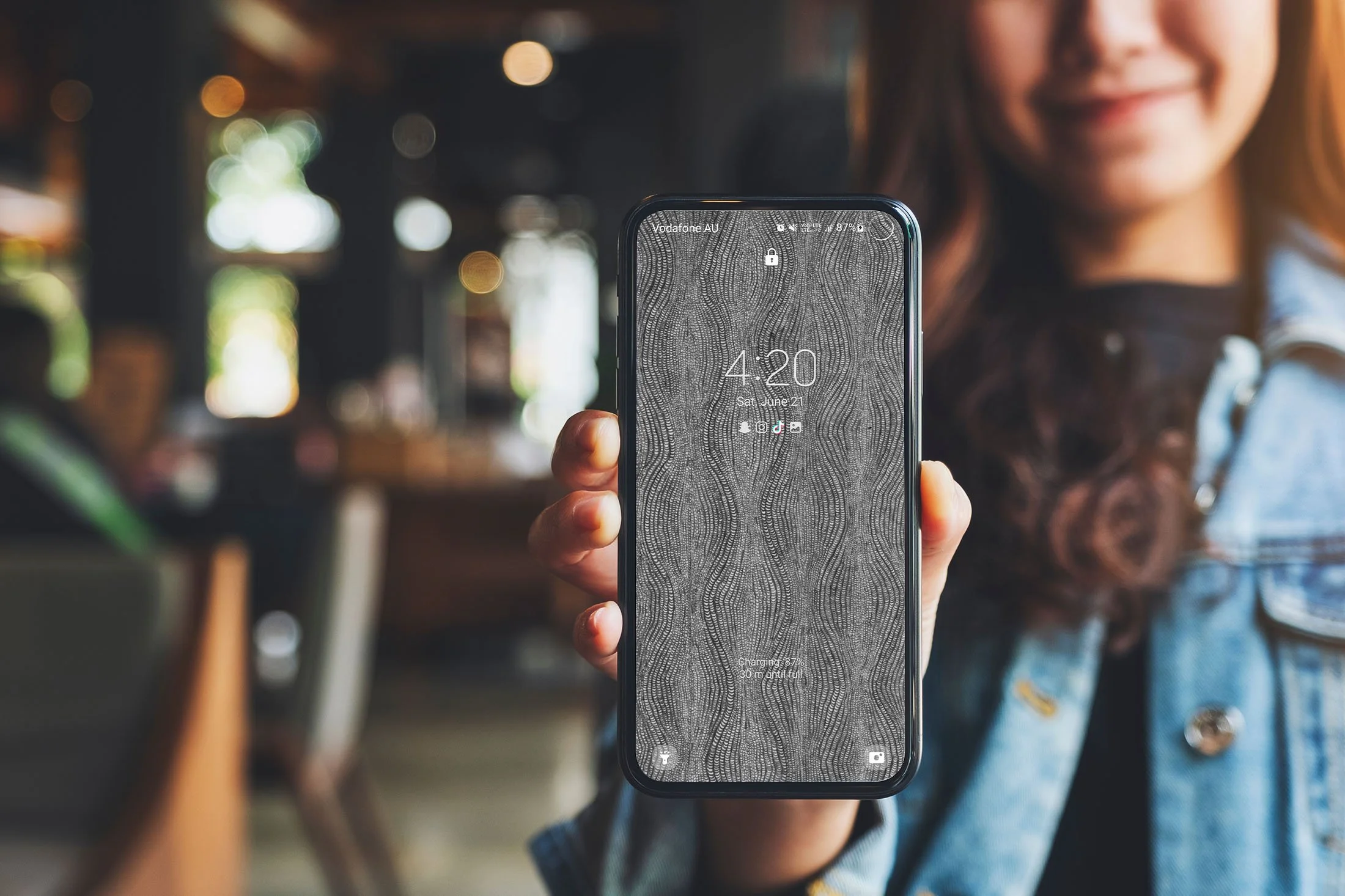 Girl-holding-Samsung-phone-with-black-and-white-line-art-wallpaper-with-lockscreens-over-cafe-background.jpg