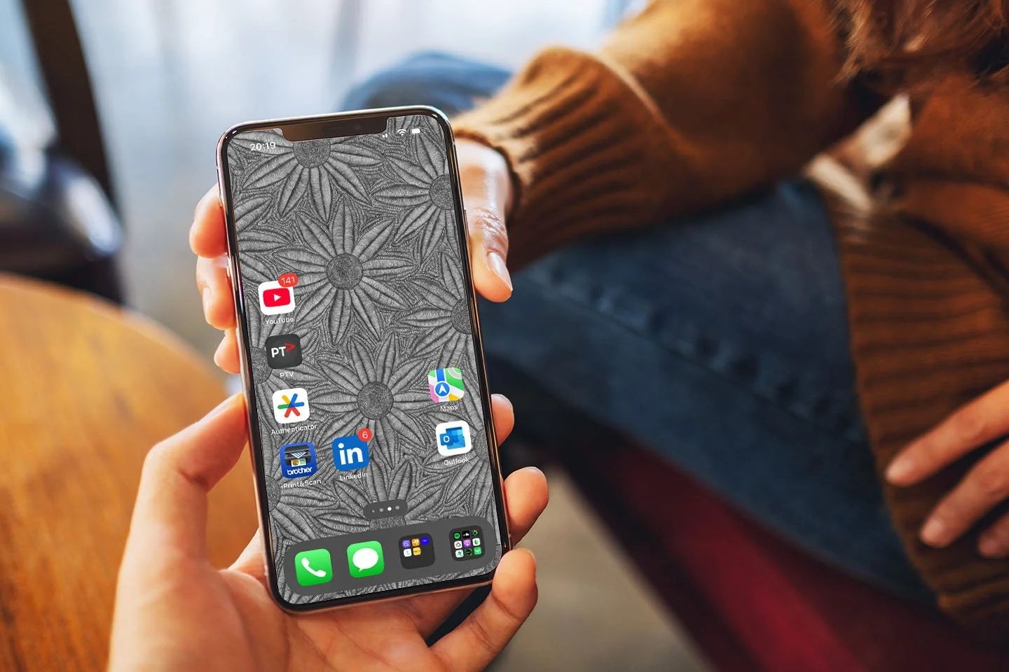 Iphone-with-black-and-white-line-art-wallpaper-with-app-icons-person-handing-phone-to-another-person-two-hands.jpg