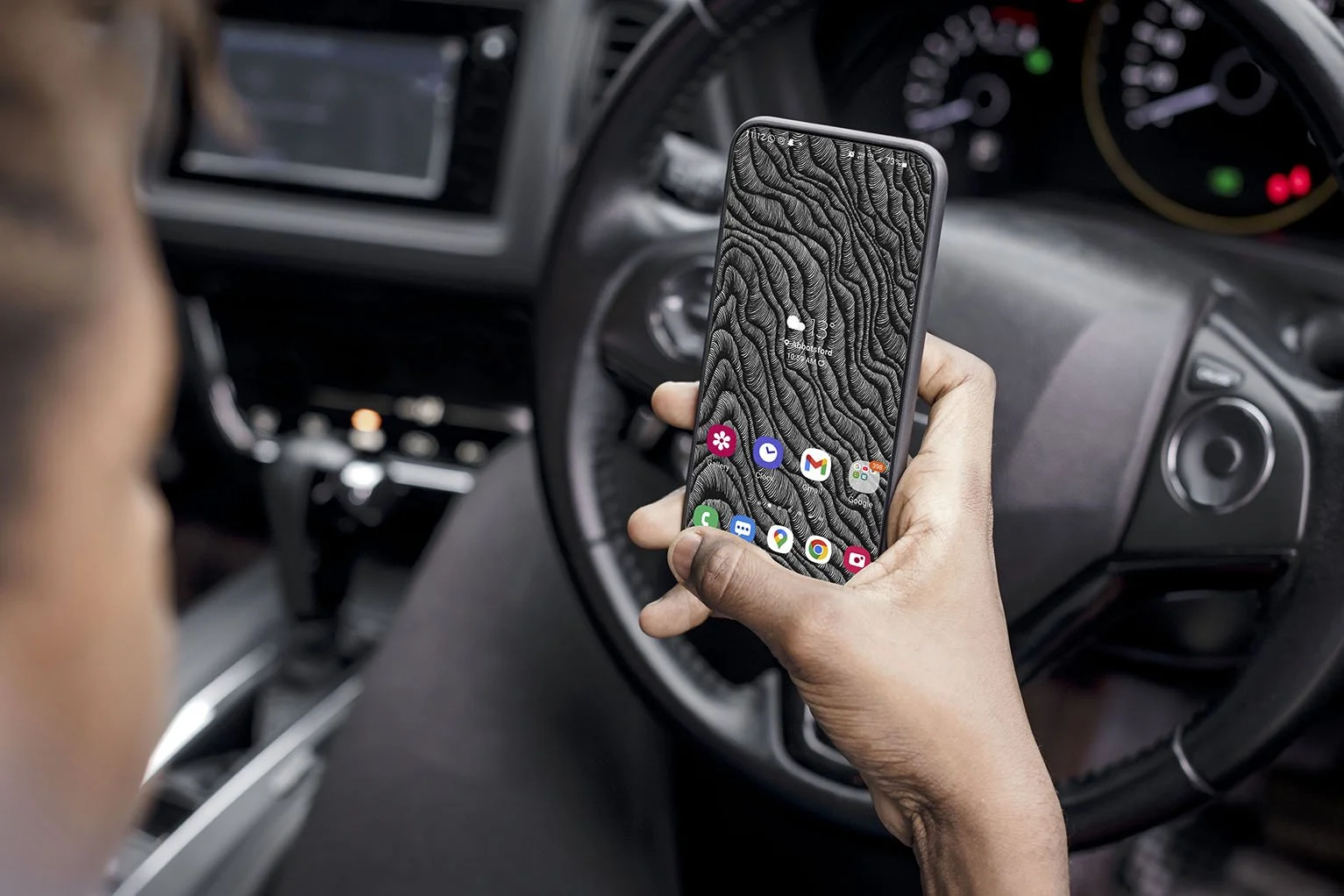 Man-sitting-in-car-holding-iphone-with-black-and-white-line-art-wallpaper-with-app-icons