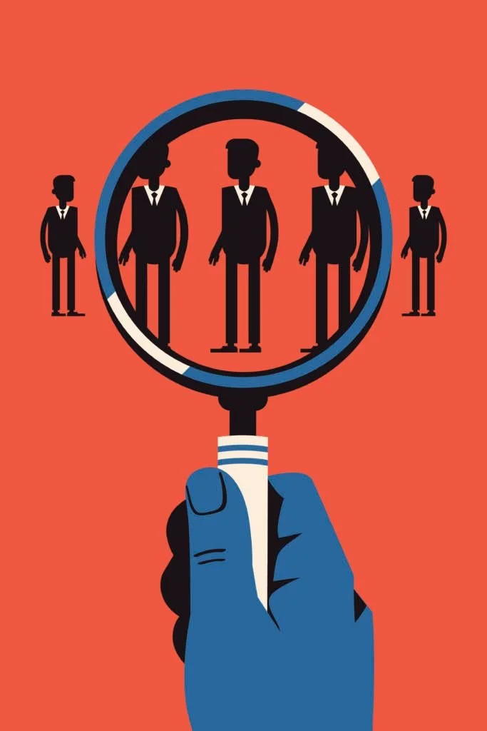 A hand holding a magnifying glass with silhouettes of people inside, symbolizing focus on or search for individuals.
