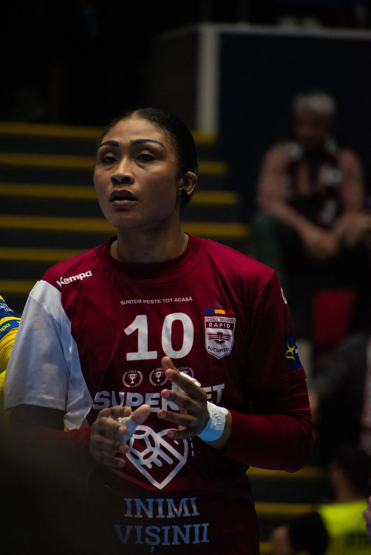 Jogadora de vôlei com uniforme vermelho e branco, número 10, no ginásio, em um jogo.