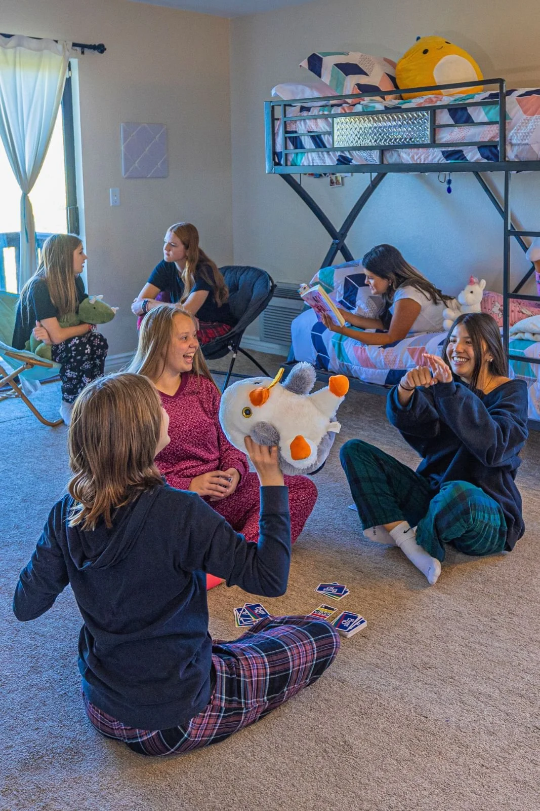 Students relaxing and laughing together in a shared bedroom, playing a card game and spending time in the evening.