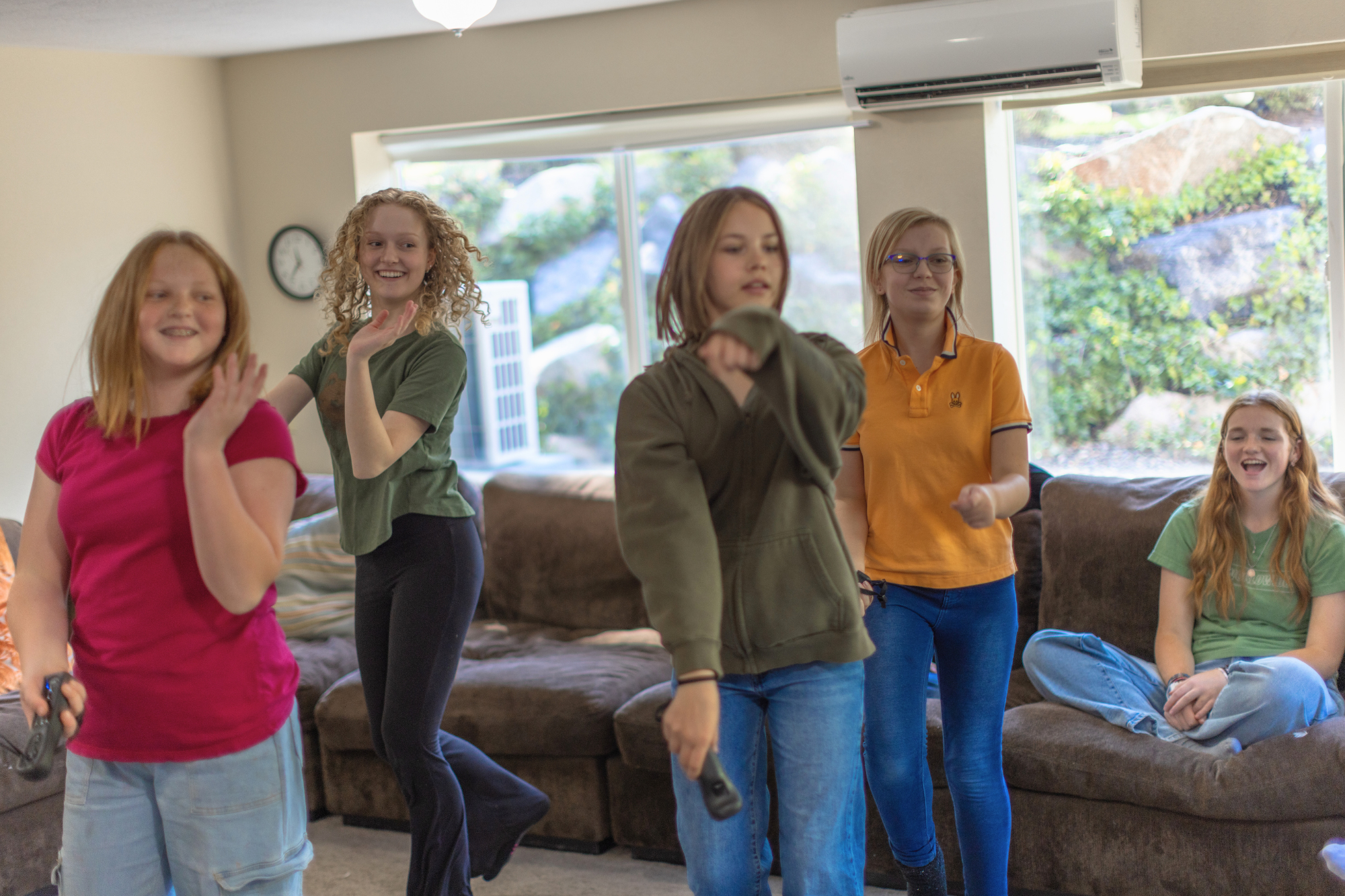 Students laughing and moving while playing a group dance game in a common room.