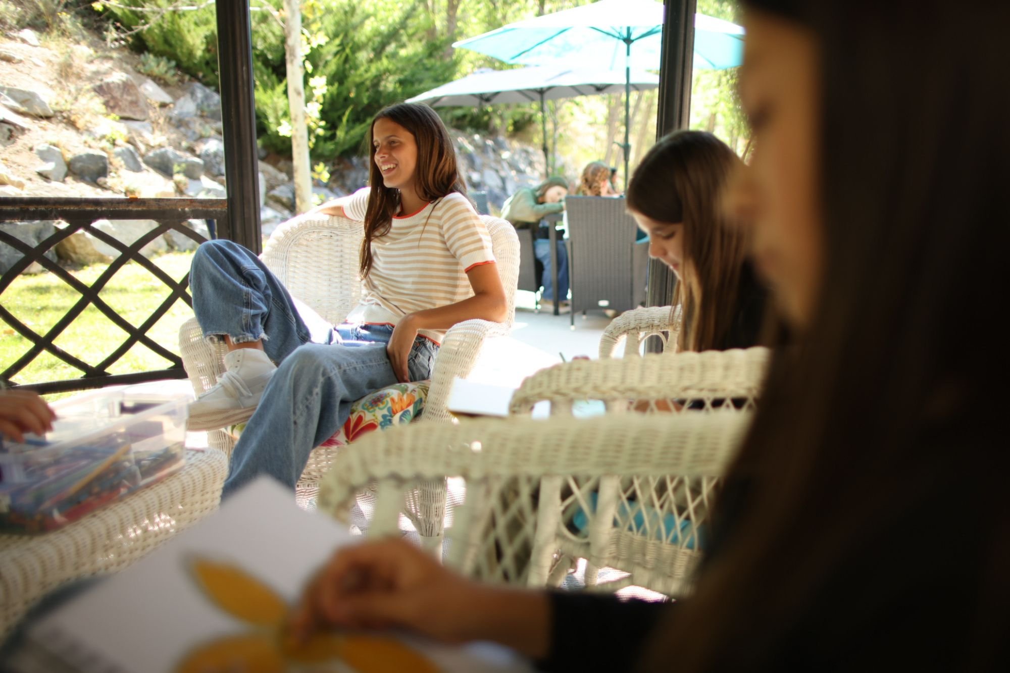 Students relaxing and talking on a sunny porch during daily life at Eva Carlston Academy.