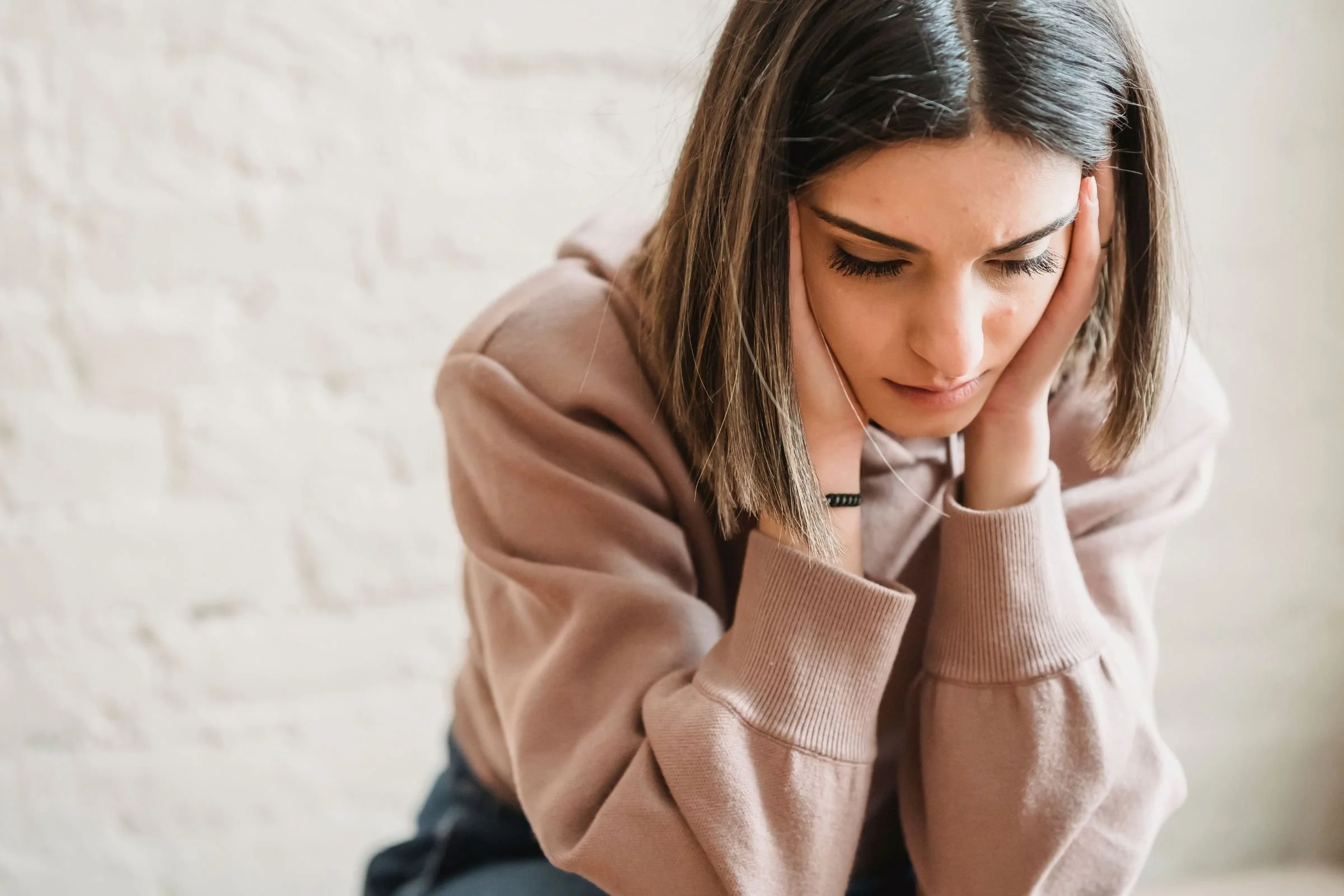 A young woman resting her head in her hands while coping with adolescent depression.
