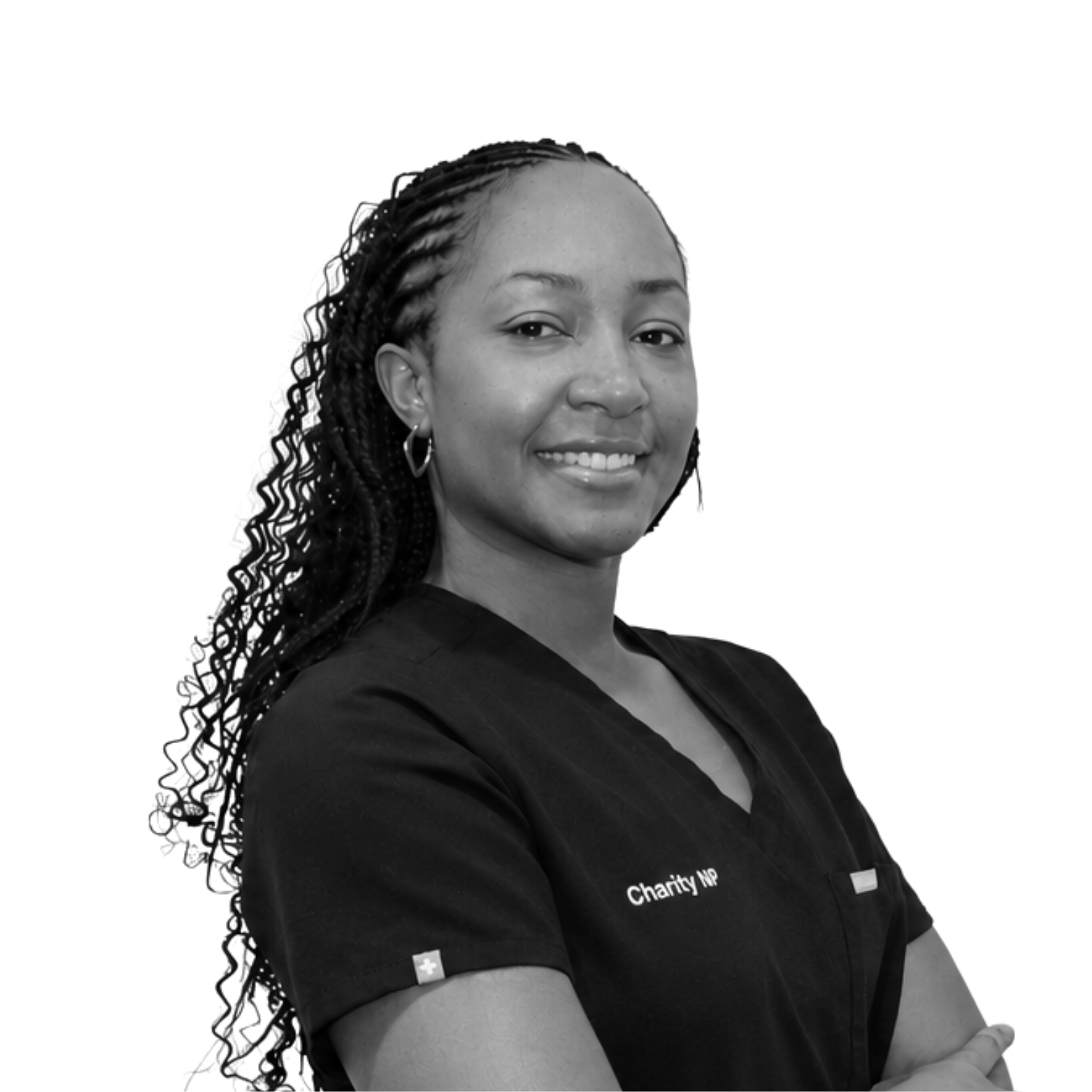Black and white photograph of a woman smiling, wearing a black shirt with the word 'Charity NP' embroidered on it, and name tag 'FIGS', with long dreadlocks and hoop earrings.