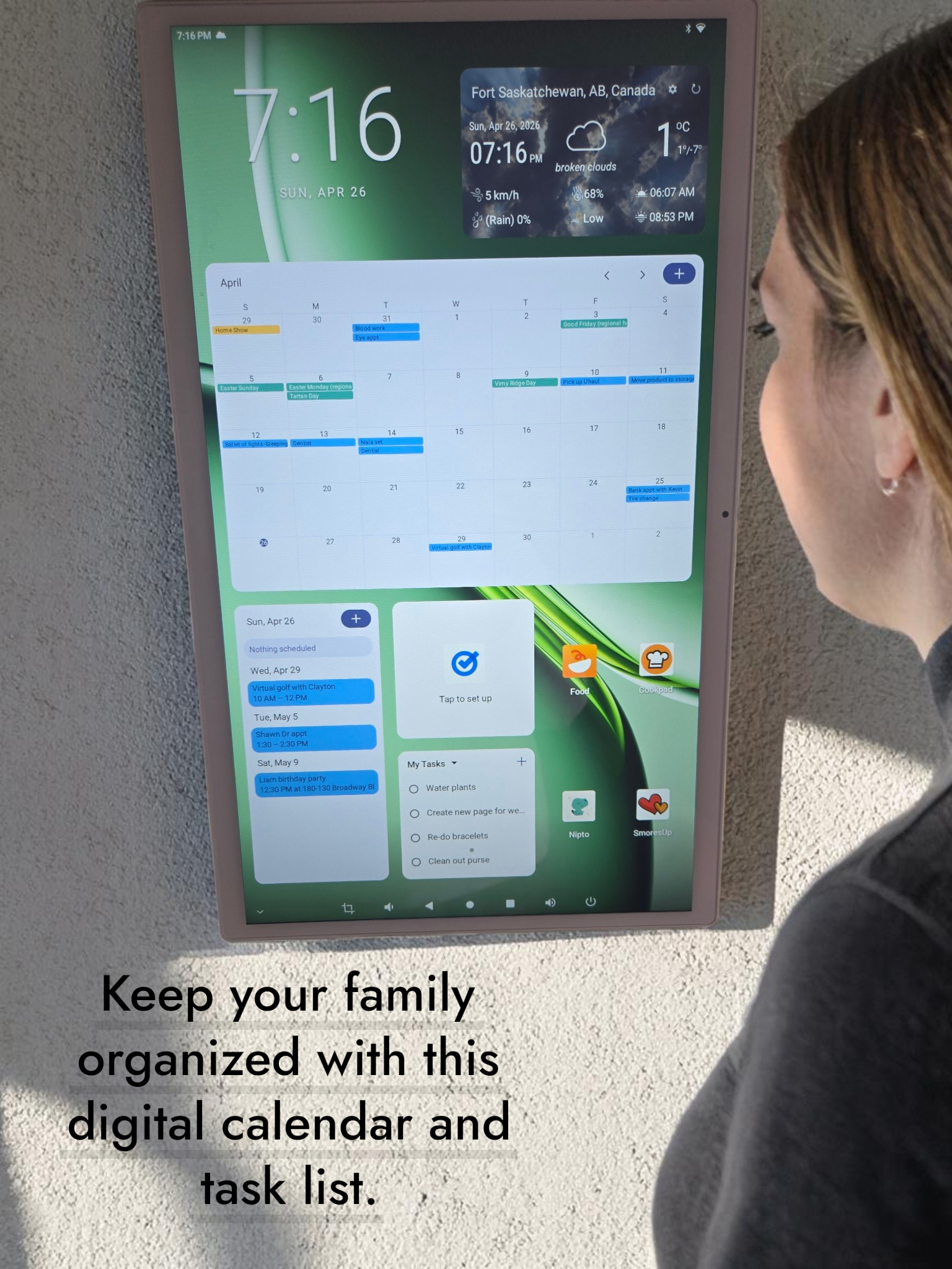 A digital tablet mounted on a wall displaying a calendar and task list. This digital wall calendar connect to you phone to keep your family organized where ever you are.