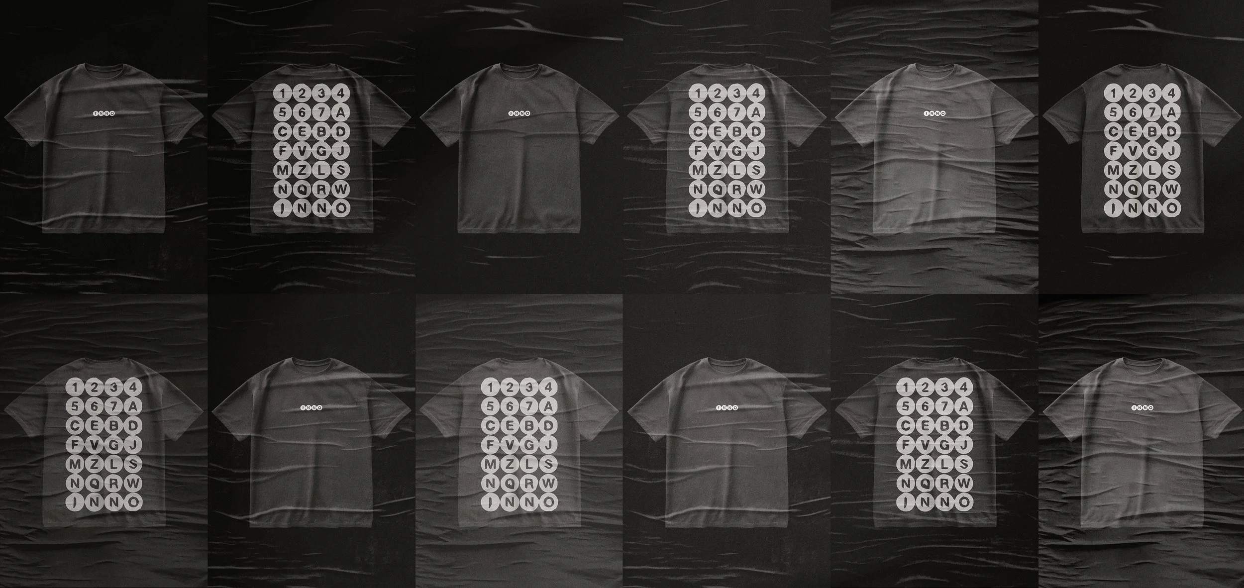 A grid of ten black T-shirts with white graphic designs, laid flat on a black textured surface. The designs on most T-shirts feature a circular arrangement of circles containing numbers and letters, while a few shirts are plain with just a small logo or text.