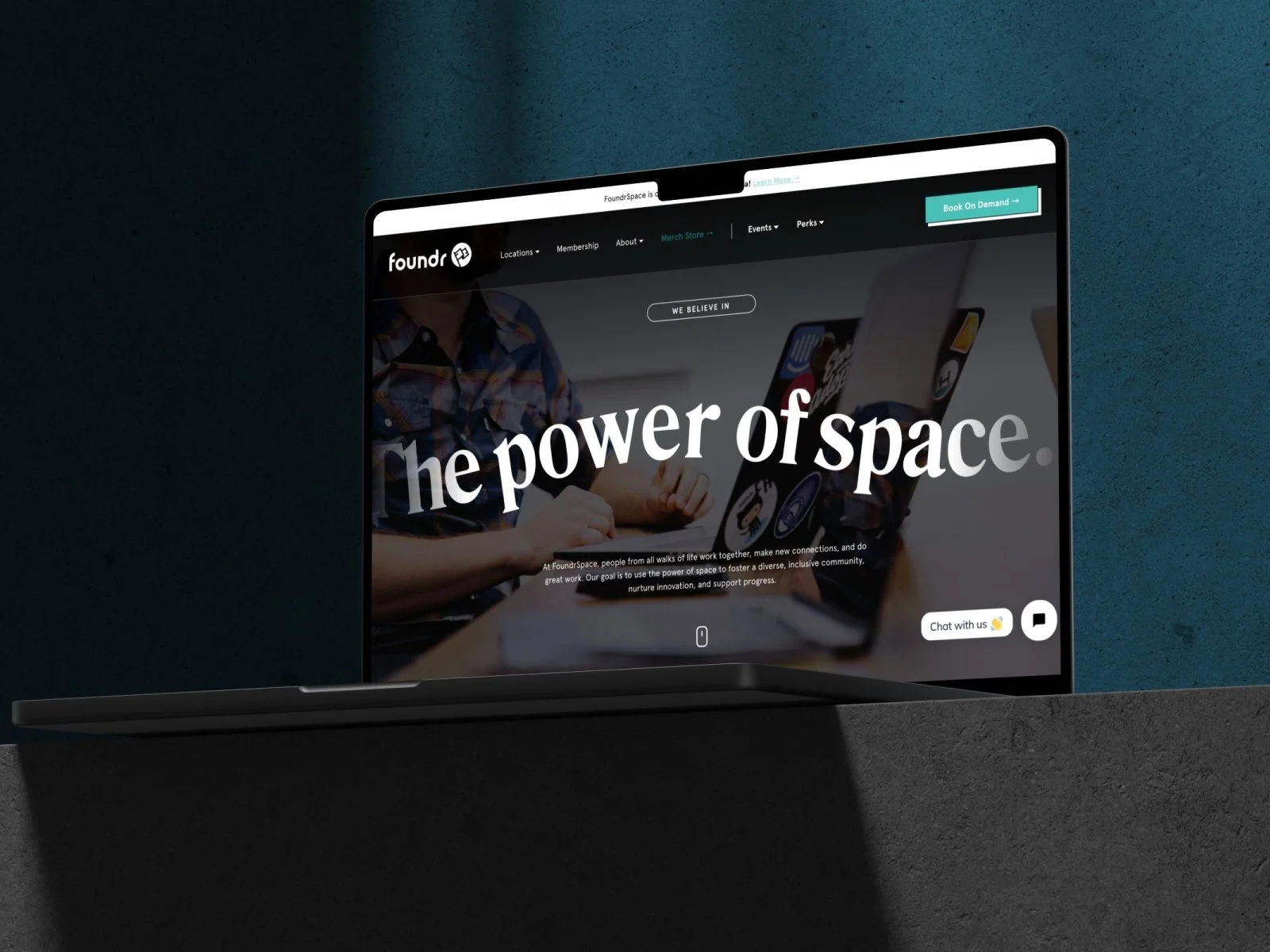Laptop displaying FoundrSpace website with the text 'The power of space' and a chat support icon.