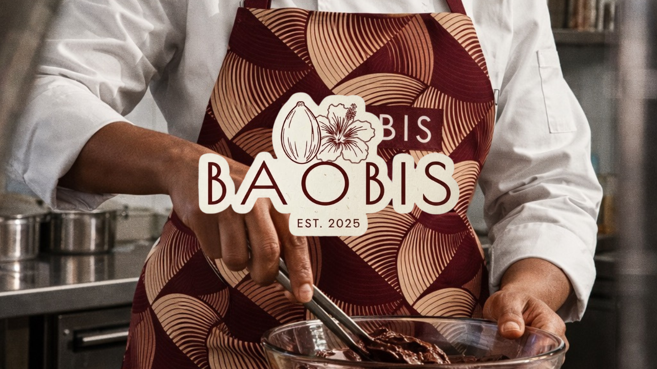 Person wearing a patterned apron and white chef coat mixing chocolate in a glass bowl in a kitchen.