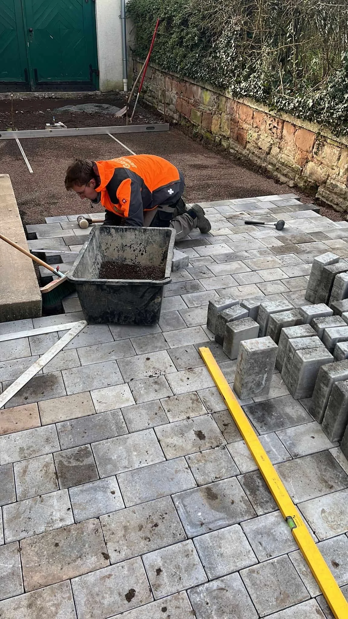 Ein Arbeiter legt Pflastersteine auf den Boden.