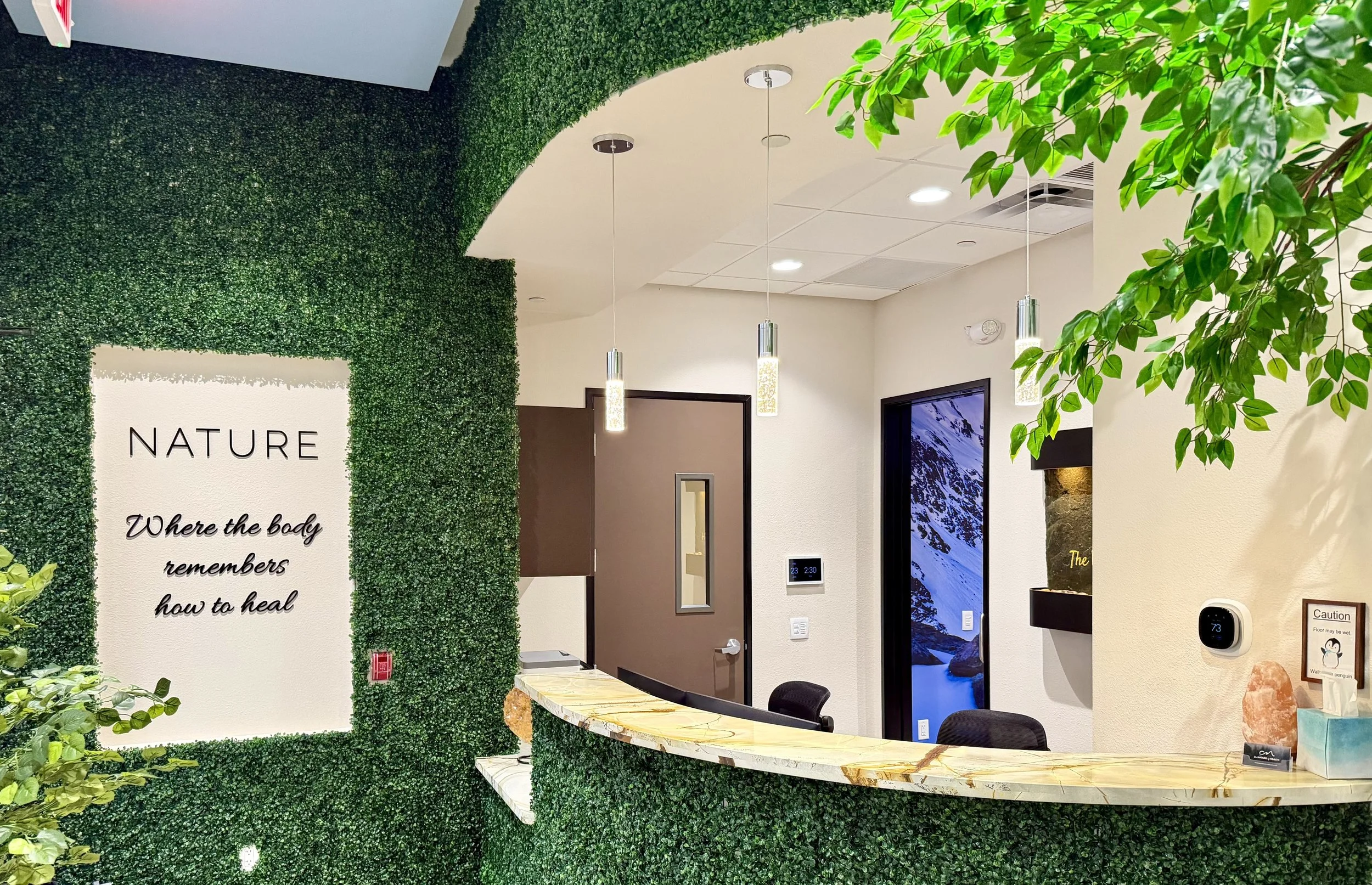 Front reception desk with greenery feature wall at The Nature of Health in Gilbert, AZ