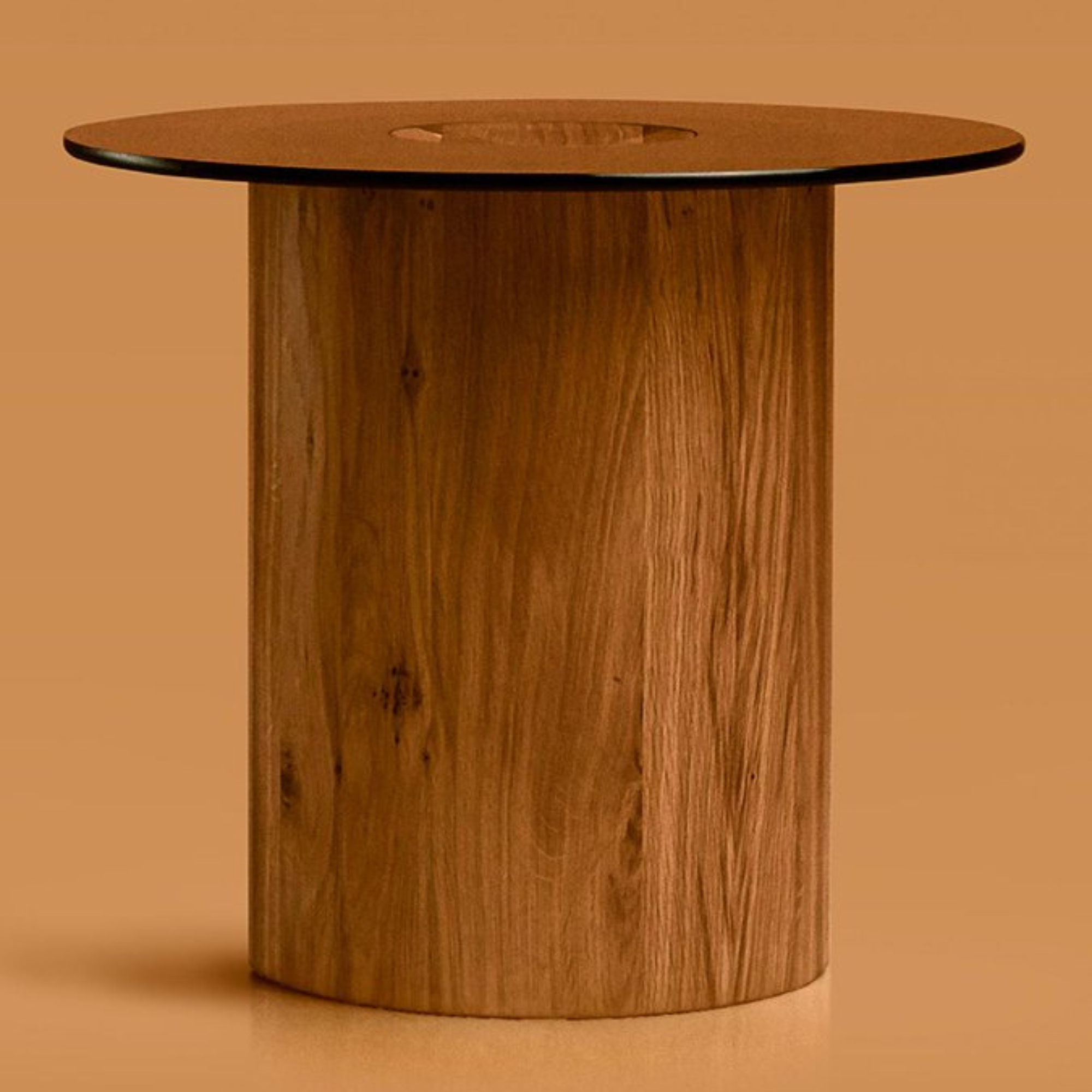 A side table from the Columns collection featuring a massive, singular solid oak cylindrical base supporting a circular natural leather top.