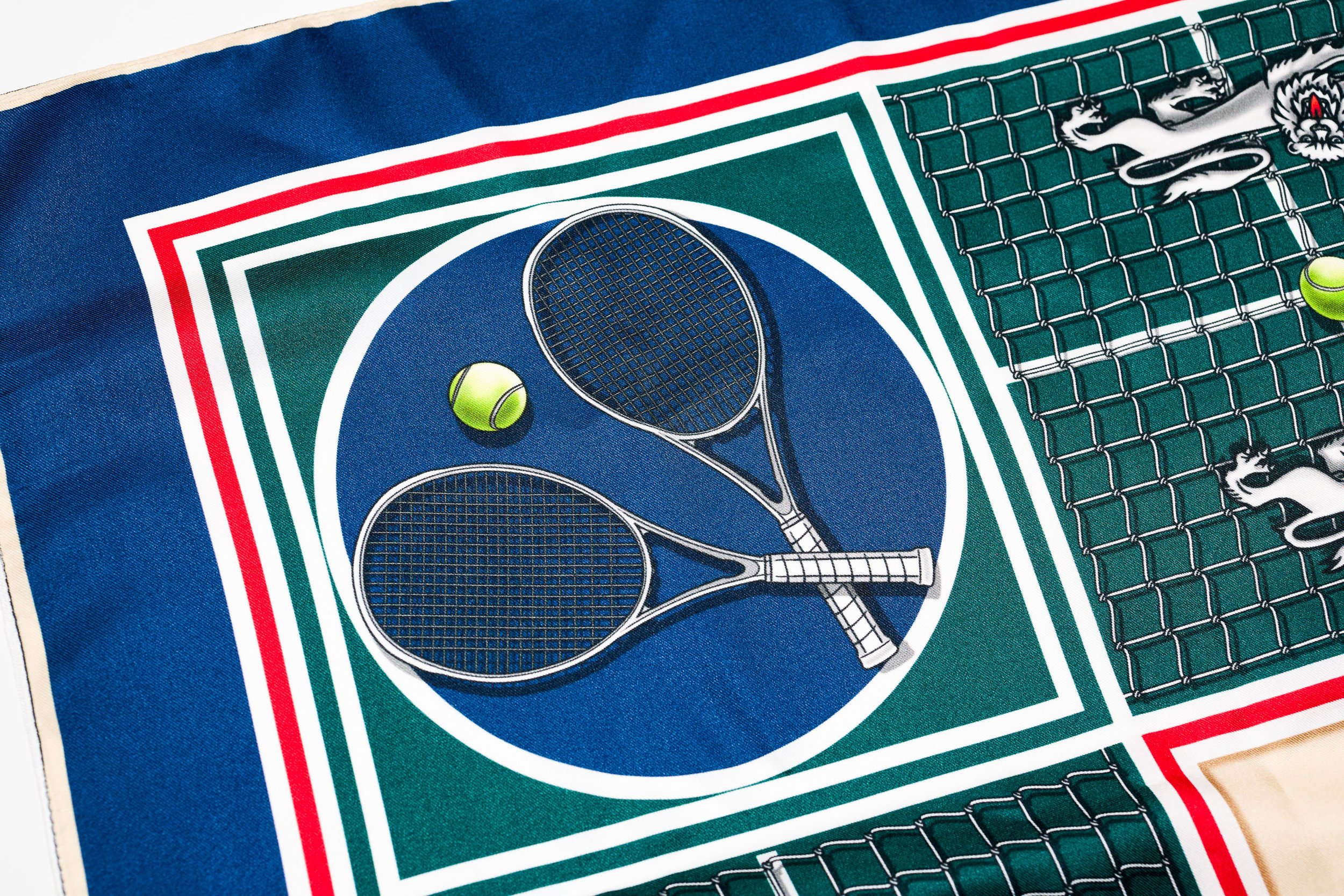 A high-detail close-up of a bespoke silk scarf from the Objects of Affection Collection, featuring intricate illustrations of tennis racquets and heraldic lions, representing the PLCFA principle of material singularity.