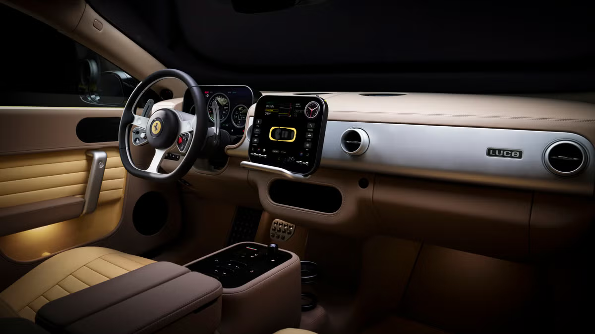 Interior dashboard view of the Ferrari Luce EV showing a beige leather cabin, a minimalist three-spoke steering wheel with a Prancing Horse emblem, a central floating digital display monitor, and clean aluminum accents labeled LUCE.
