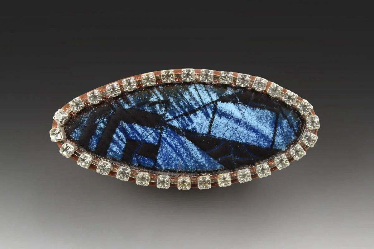 A brooch by Robert Ebendorf, a case study in Post-Luxury Conceptual Functional Art, featuring a vibrant blue butterfly wing set against found materials and diamonds.