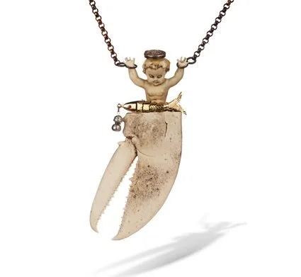 A studio photograph of a brooch by Robert Ebendorf, featuring an assemblage of found objects: a large, weathered crab claw hangs from a small cherub figurine, which is attached to a chain.