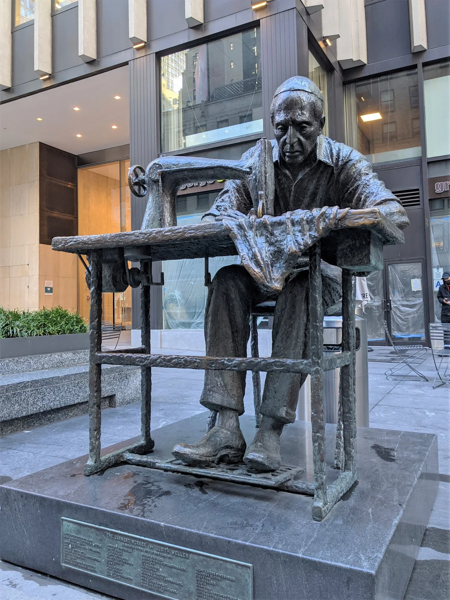 Bronze statue titled The Garment Worker by Judith Weller on Seventh Avenue in New York, depicting a tailor operating a manual sewing machine.