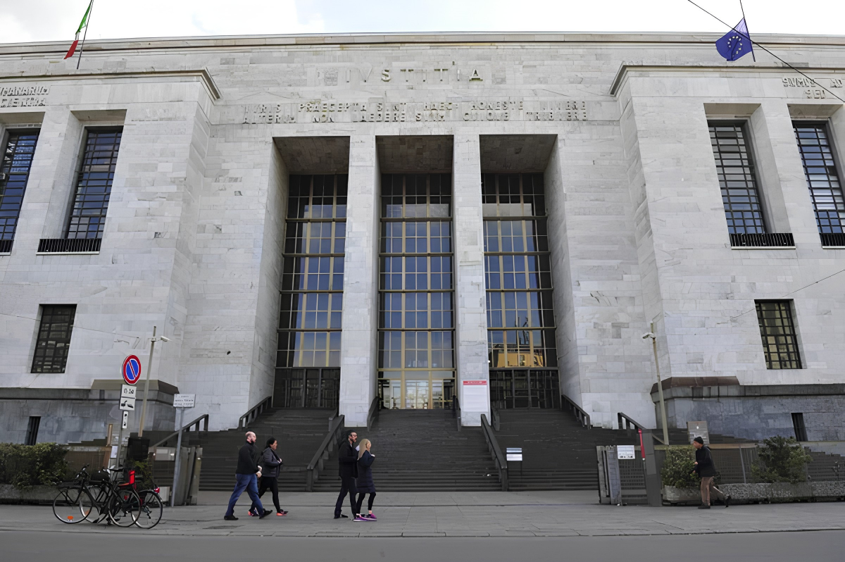 The exterior marble facade of the Palazzo di Giustizia, the Tribunal of Milan courthouse in Italy, displaying classic rationalist architecture and the inscription Iustitia above the entrance.