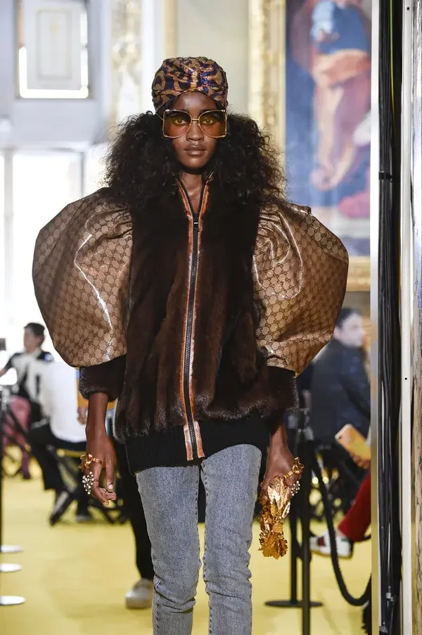 A model on the Gucci Resort 2018 runway wearing a fur-paneled bomber jacket with large, monogrammed logo sleeves, a direct appropriation of a 1989 Dapper Dan design.