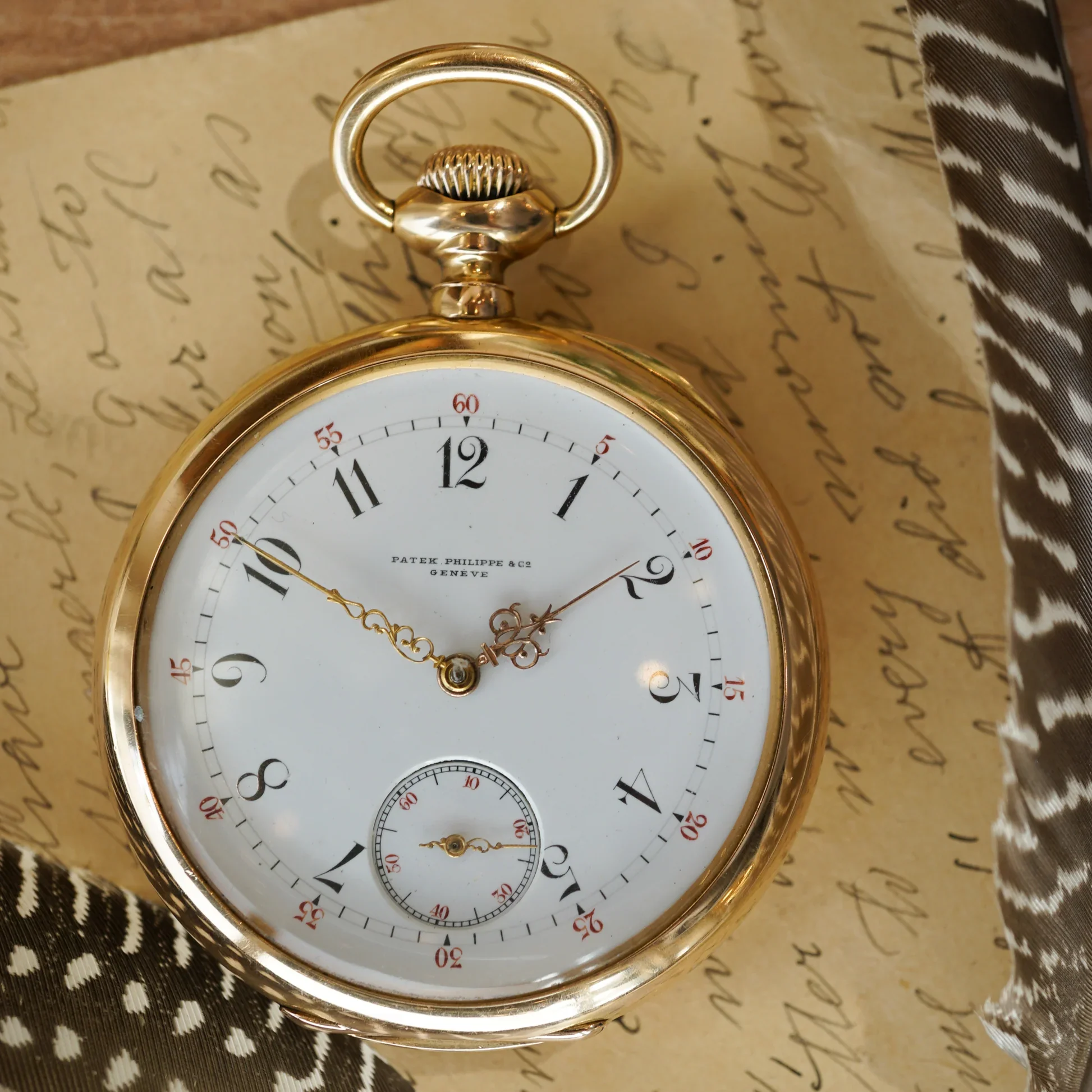 A close-up of a gold heirloom Patek Philippe pocket watch, illustrating the concept of an inalienable object with deep narrative value, resting on a historic handwritten letter.