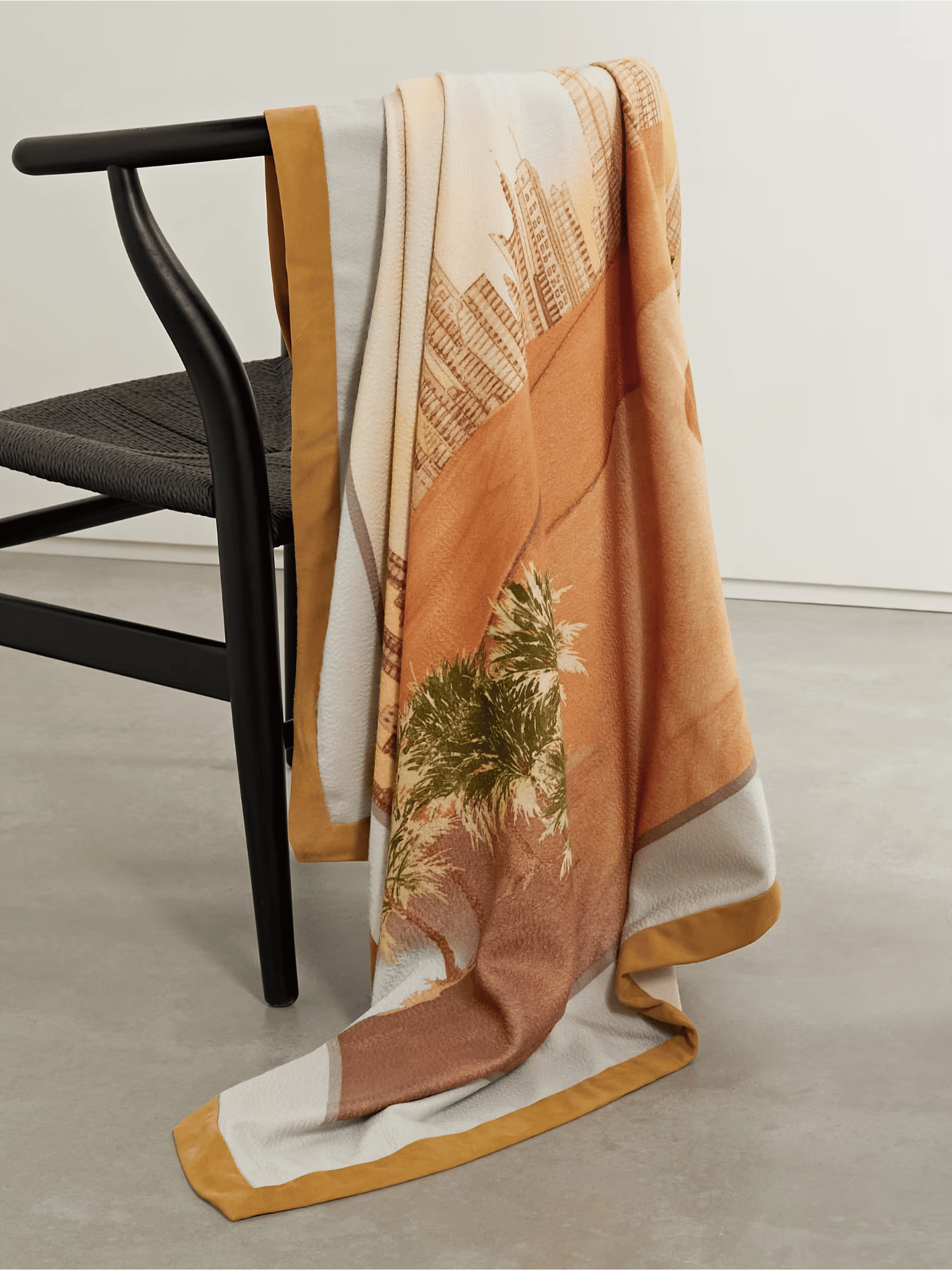 A Loro Piana cashmere throw blanket embodying quiet luxury, draped over a minimalist black chair, showcasing timeless design and superior craftsmanship.