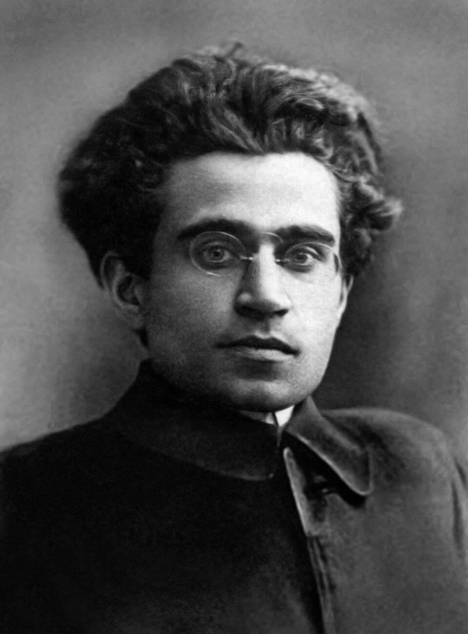 A historical black and white portrait of Antonio Gramsci wearing wire-rimmed glasses, used by Denise Ferreira da Silva to trace the boundaries of intellectual function within the architecture of liberal capital.